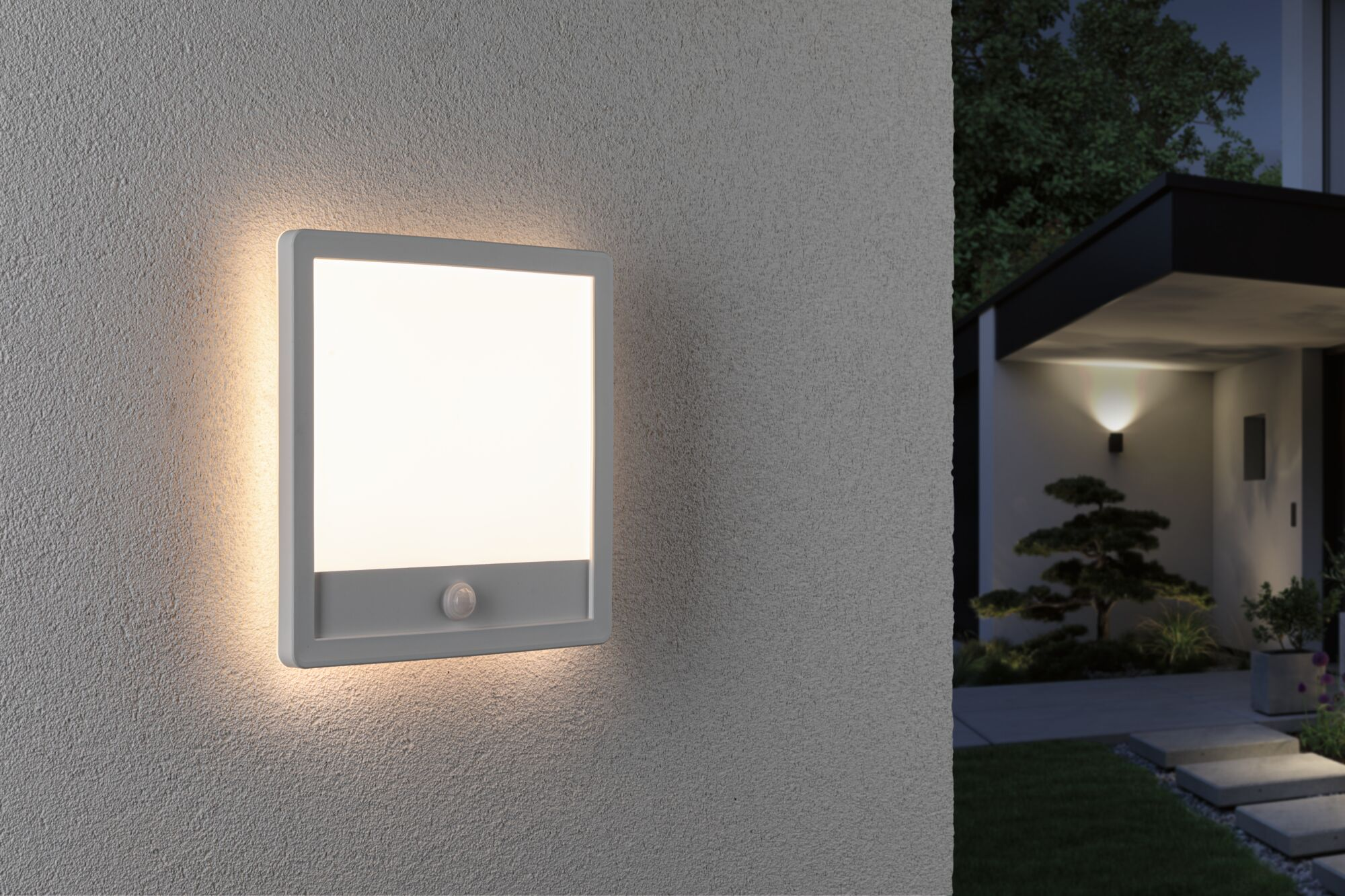 Eine quadratische weiße Außenleuchte mit Sensor ist an einer strukturierten grauen Wand montiert.