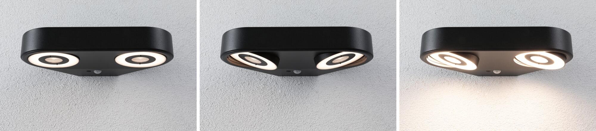 Eine schwarze moderne Wandleuchte mit zwei verstellbaren runden LED-Lichtquellen an einer strukturierten weißen Wand.