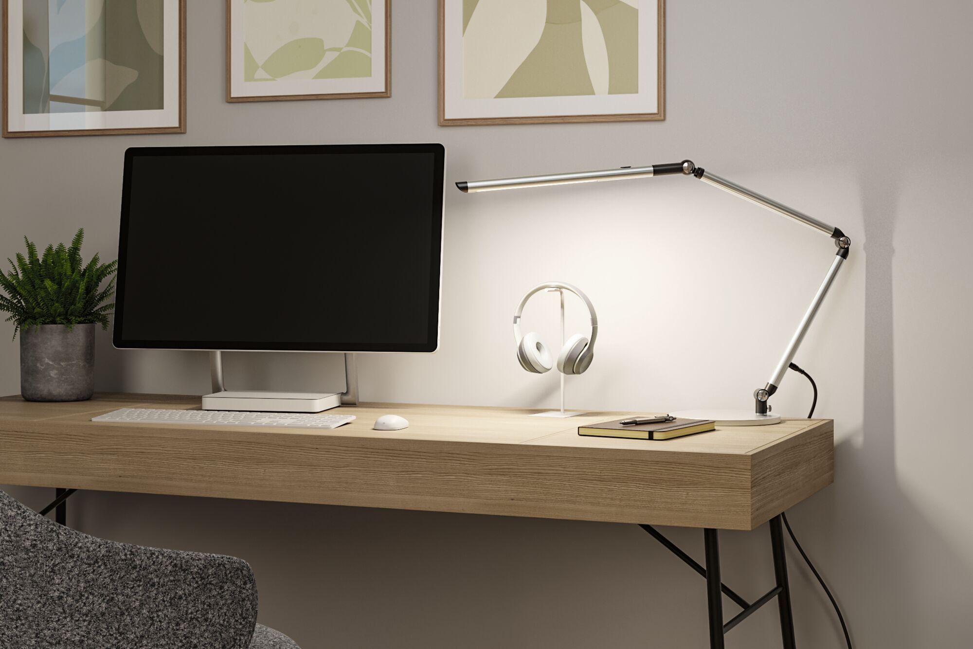 Ein Holztisch mit PC, Tastatur, Lampe, Kopfhörern, Notizbuch und einer Topfpflanze.