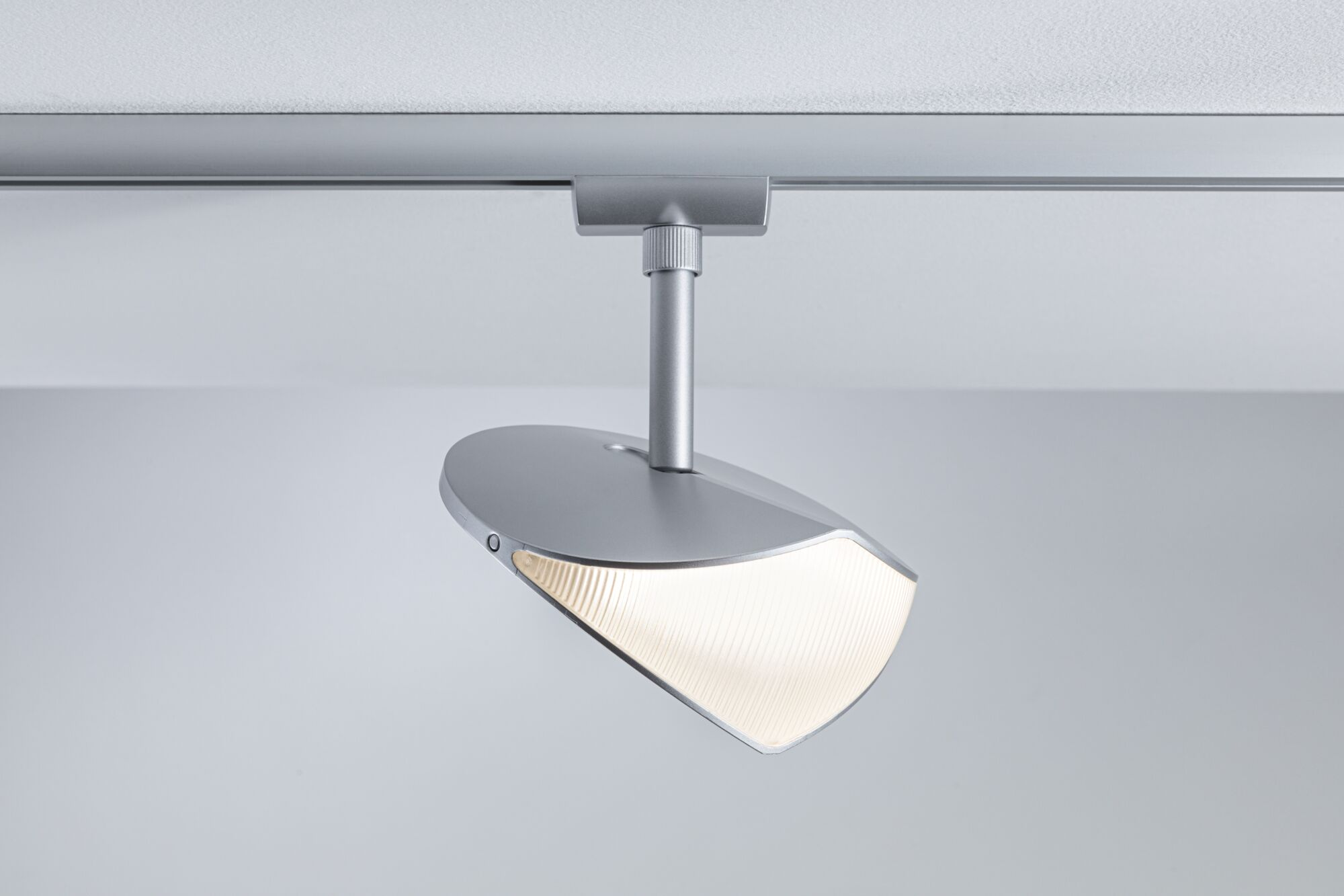 Moderne silberne Schienenleuchte mit geripptem, leuchtendem Diffusor an der Decke.