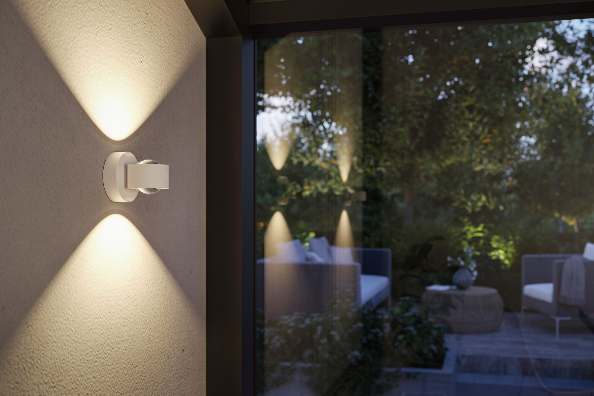 Eine weiße Wandlampe strahlt Licht nach oben und unten ab, mit Blick auf einen Garten durch ein Fenster.