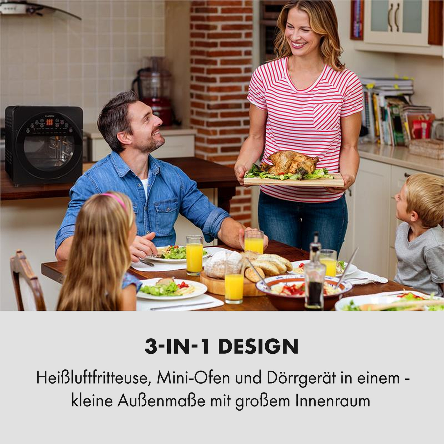Eine Familie sitzt am Esstisch in einer Küche, während eine Frau gebratenes Hähnchen serviert.
