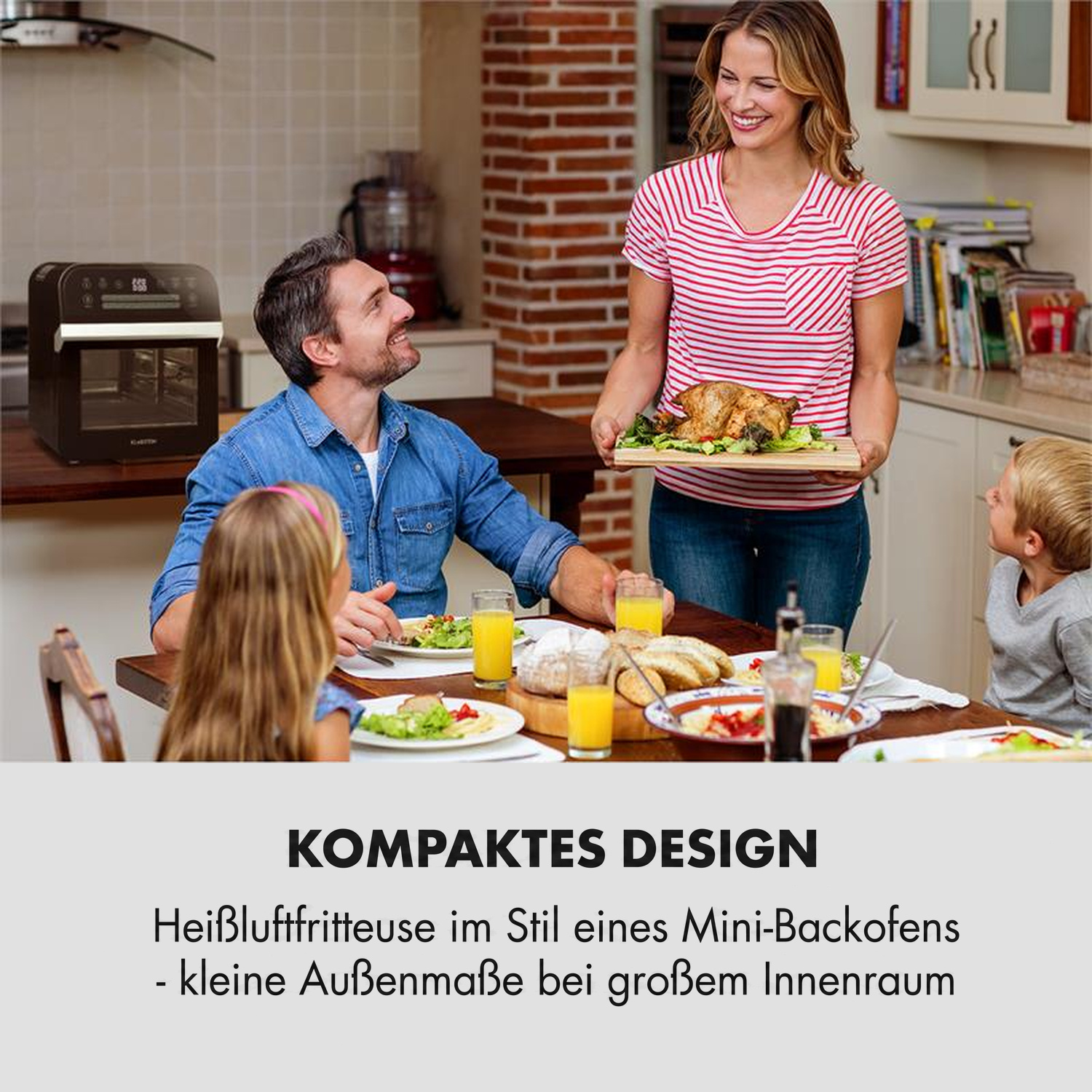 Eine Familie sitzt am Esstisch in einer Küche, während eine Frau ein gebratenes Hähnchen serviert.