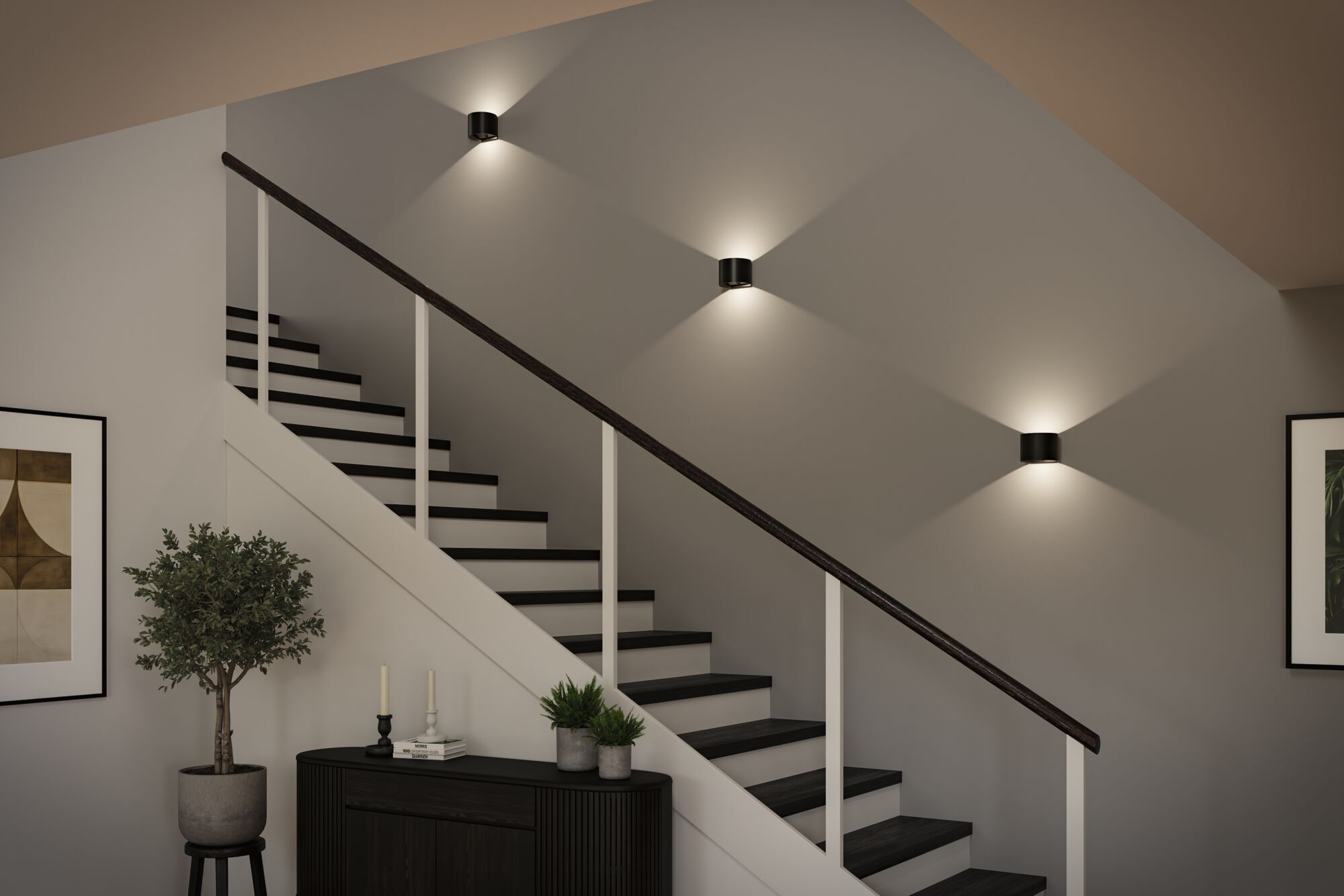 Moderne Treppe mit dunklen Stufen, weißem Geländer und drei runden Wandleuchten, die Licht an die Wand werfen.