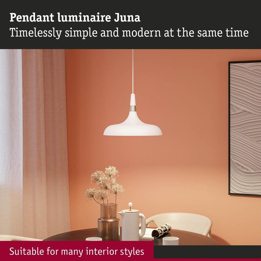 Eine weiße Pendelleuchte über einem Tisch vor einer orangefarbenen Wand mit einem gerahmten Bild.