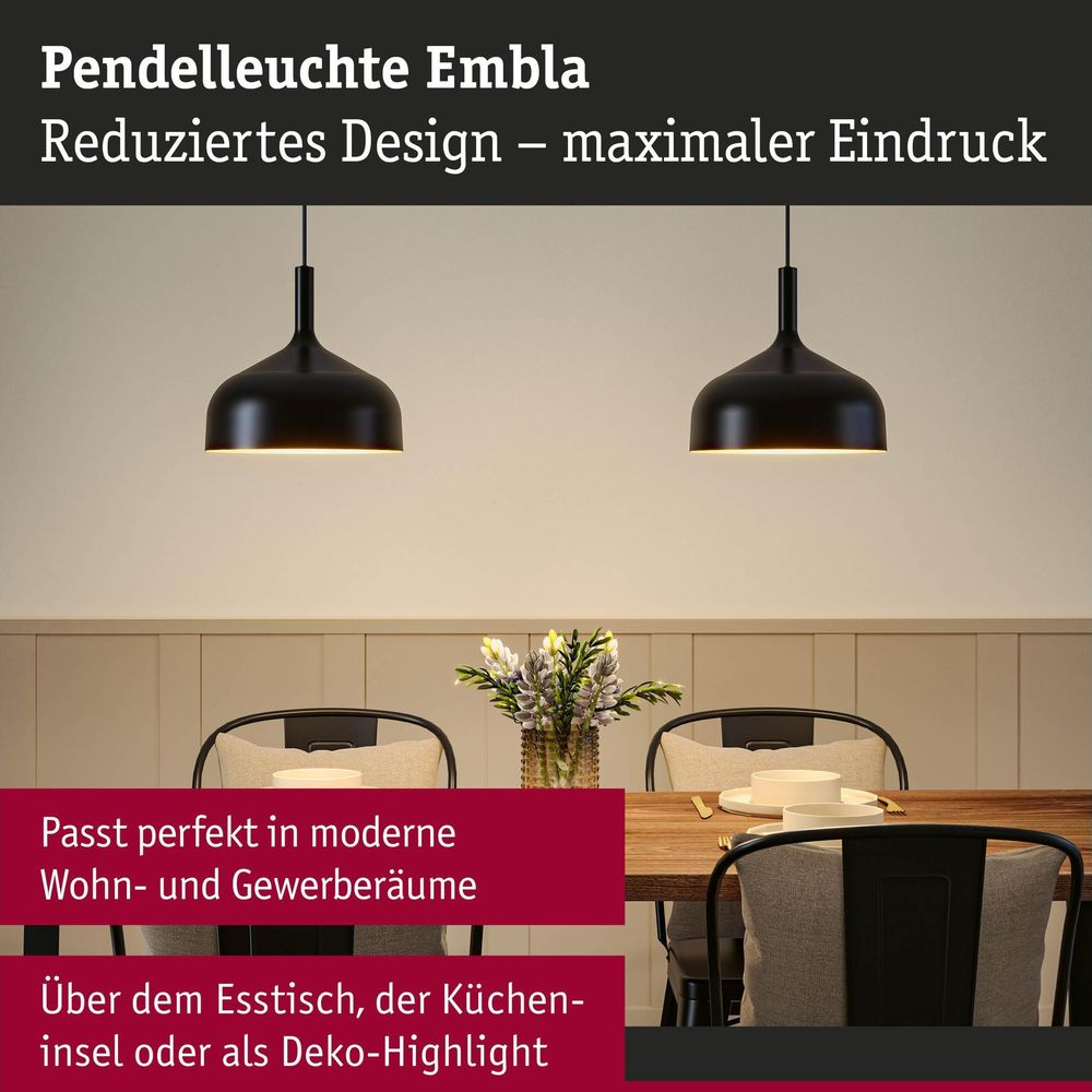 Zwei schwarze Pendelleuchten hängen über einem gedeckten Holzesstisch mit Stühlen.