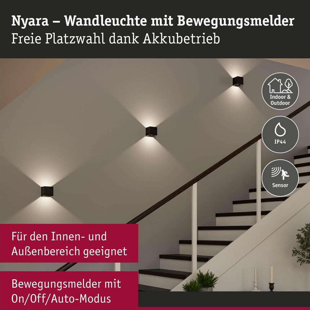 Drei schwarze Wandleuchten mit Bewegungsmeldern beleuchten eine Treppenwand, begleitet von Symbolen und deutschem Text.