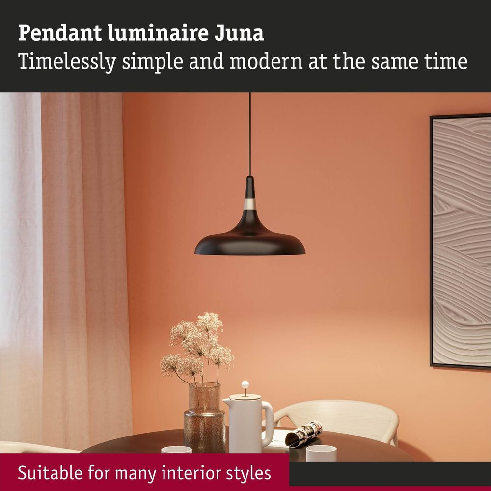 Eine schwarze Pendelleuchte über einem gedeckten Tisch vor einer pfirsichfarbenen Wand.