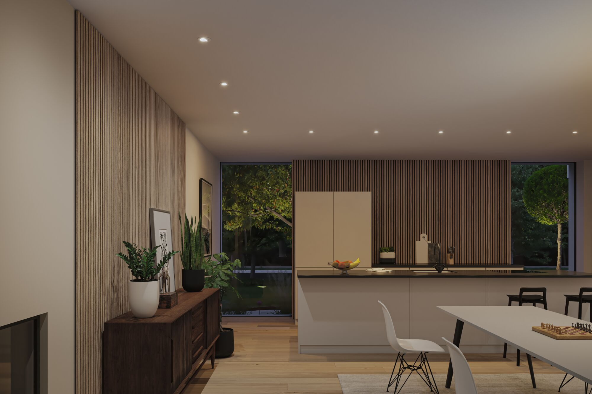 Eine moderne Küche mit Holzpaneelen, Esstisch mit Stühlen und warmen Einbauleuchten bei Nacht.