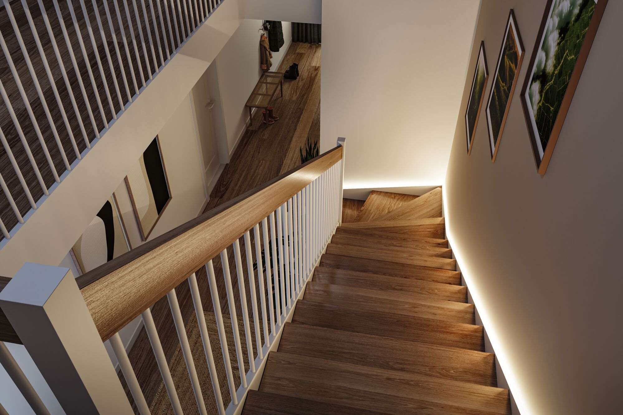 Blick von oben auf eine Holztreppe mit weißem Geländer, gerahmten Bildern an der Wand und hellem Flur unten.