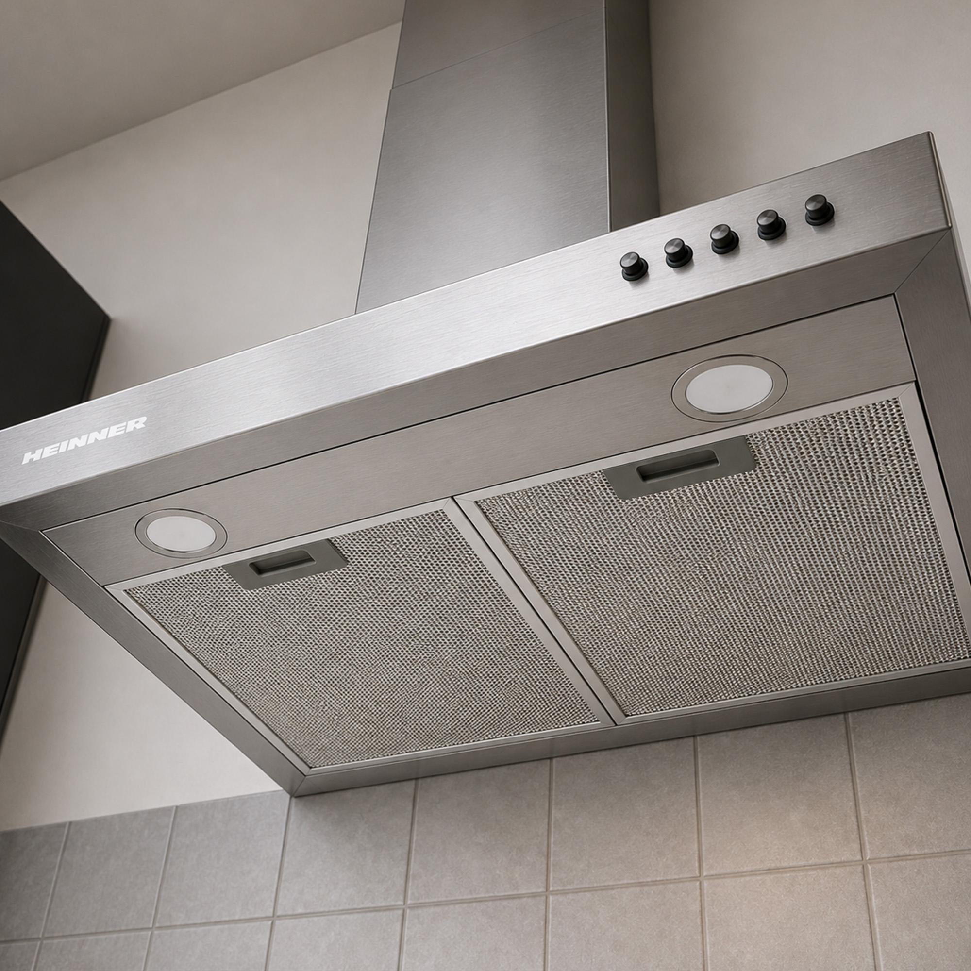 A stainless steel range hood with buttons and lights installed above grey tiles.