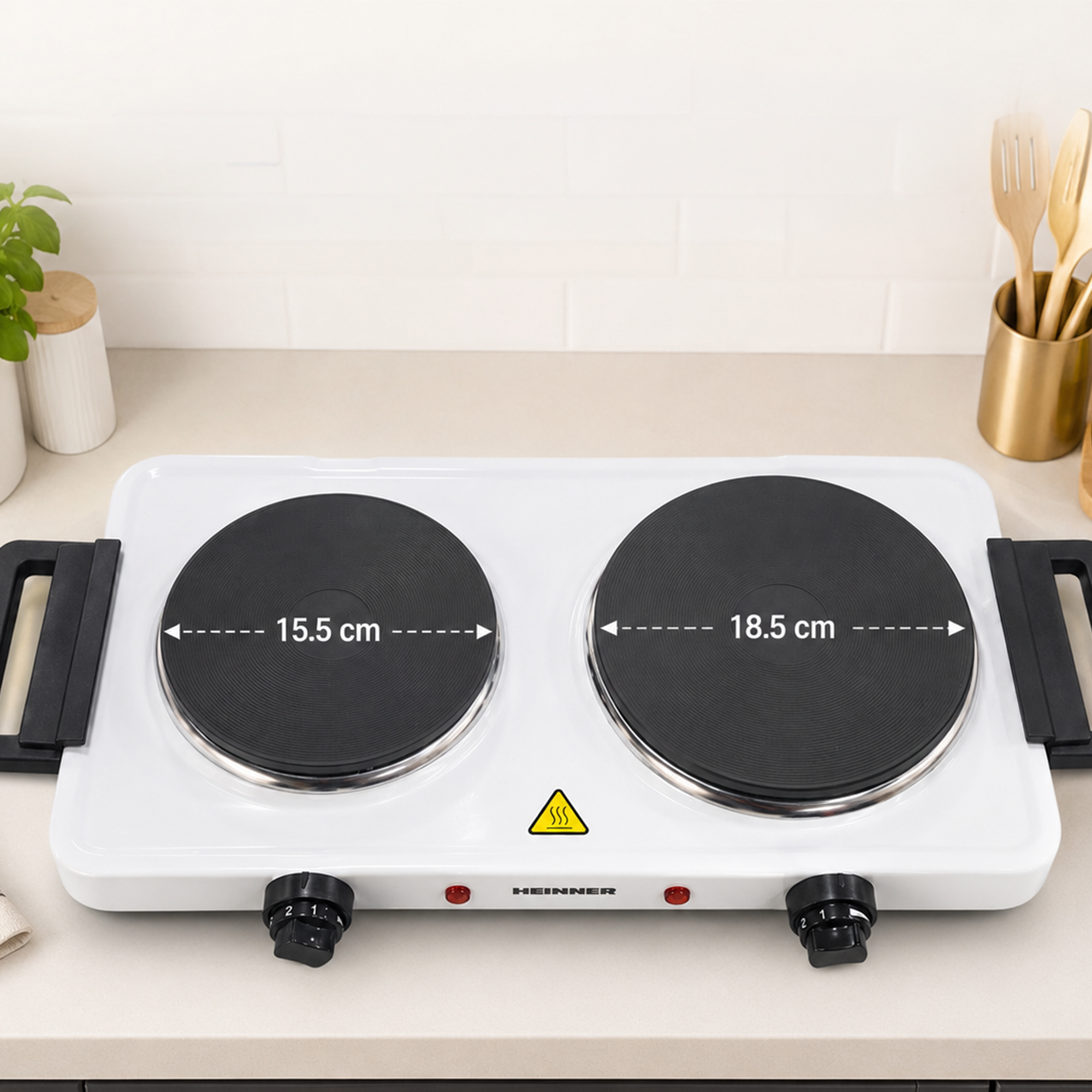 A white double hotplate with two burners, measuring 15.5 cm and 18.5 cm in diameter, placed on a kitchen counter.