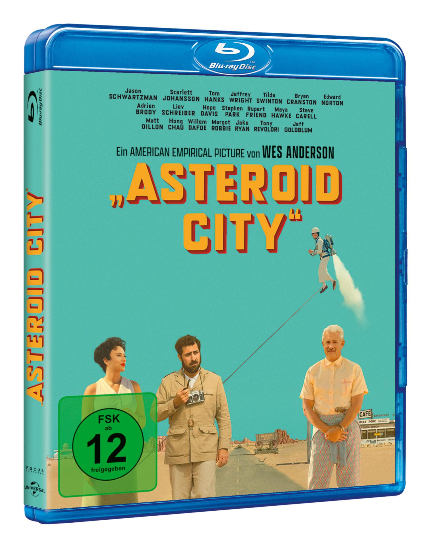 Blu-ray-Hülle des Films Asteroid City mit drei Charakteren und einer fliegenden Person vor Wüstenlandschaft.