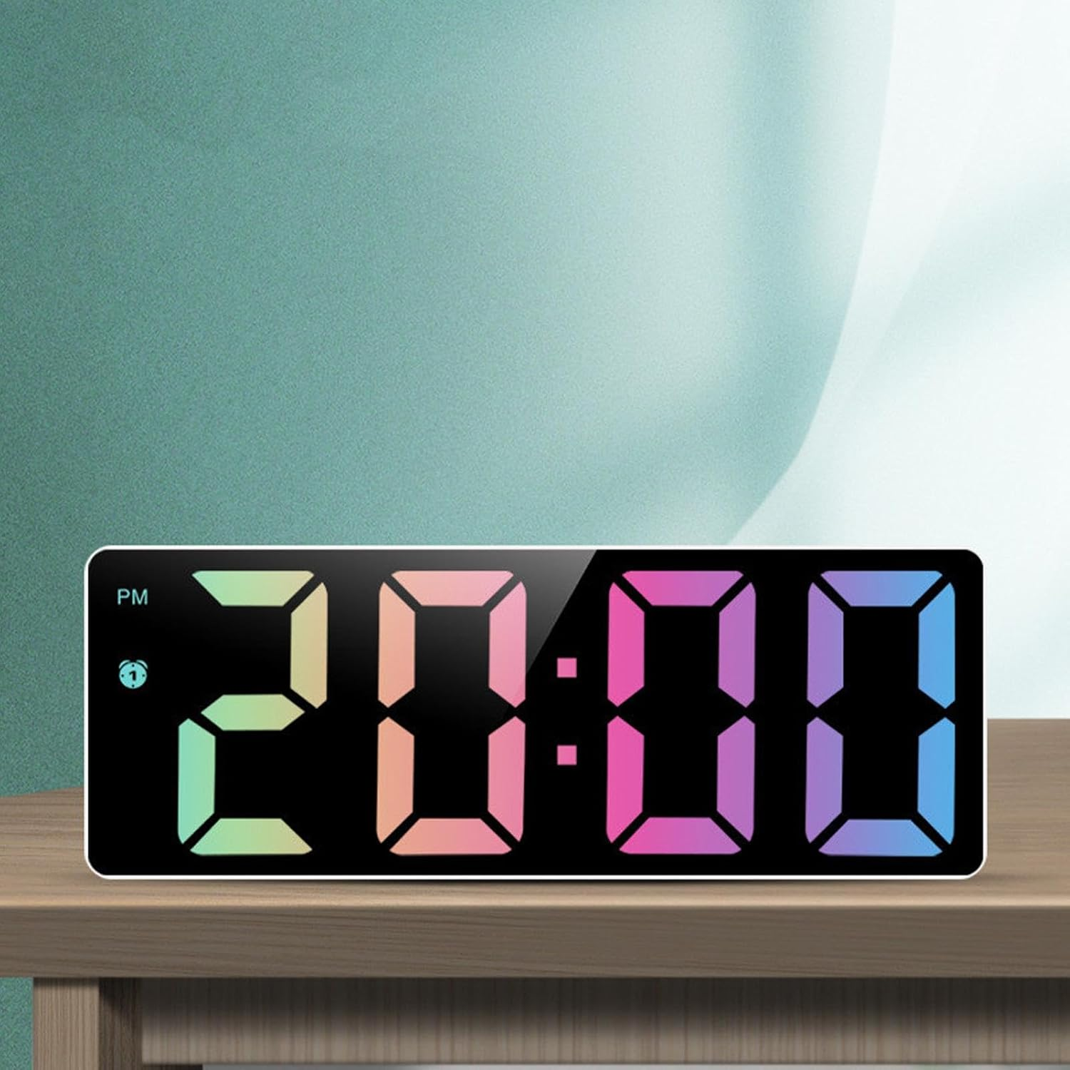Digitale LED-Uhr mit bunter Anzeige auf Holzschreibtisch vor türkisfarbener Wand.