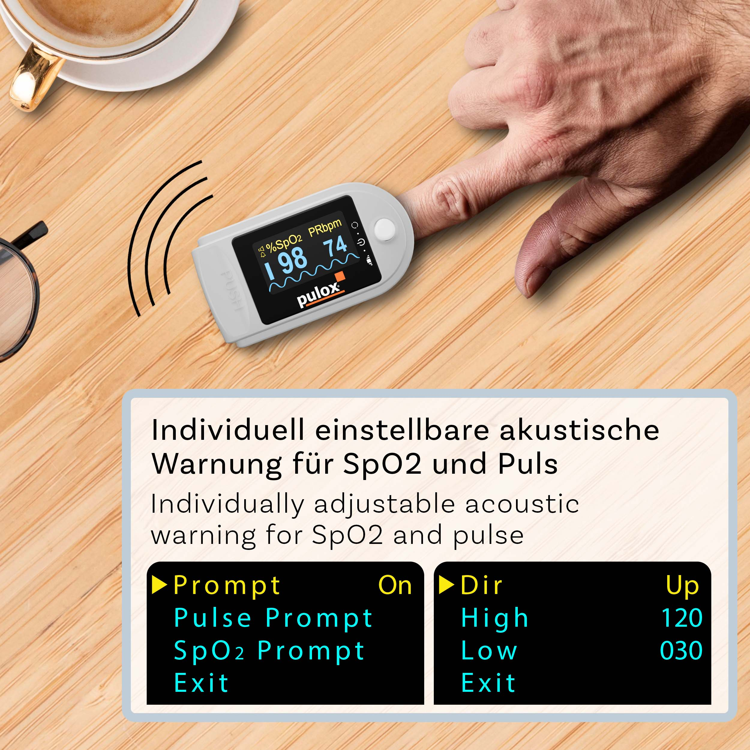 Ein Pulox-Pulsoximeter an einem Finger zeigt 98% SpO2 und 74 Puls auf hölzernem Tisch mit Kaffeetasse und Brille.