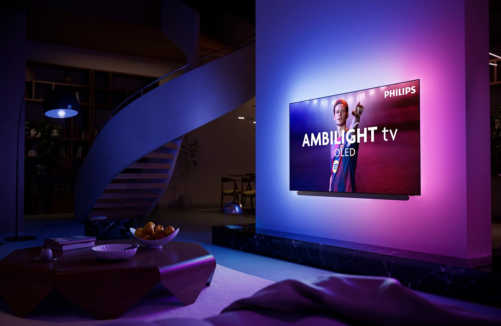 Telewizor Philips Ambilight na ścianie rzuca niebieskie i różowe światło w nowoczesnym salonie.