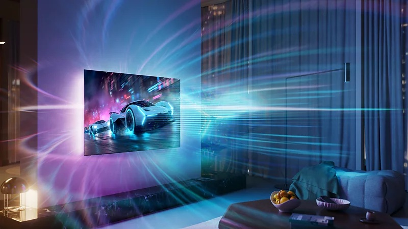 Telewizor na ścianie wyświetla samochód wyścigowy, a niebieskie i różowe światło promieniuje do pokoju.