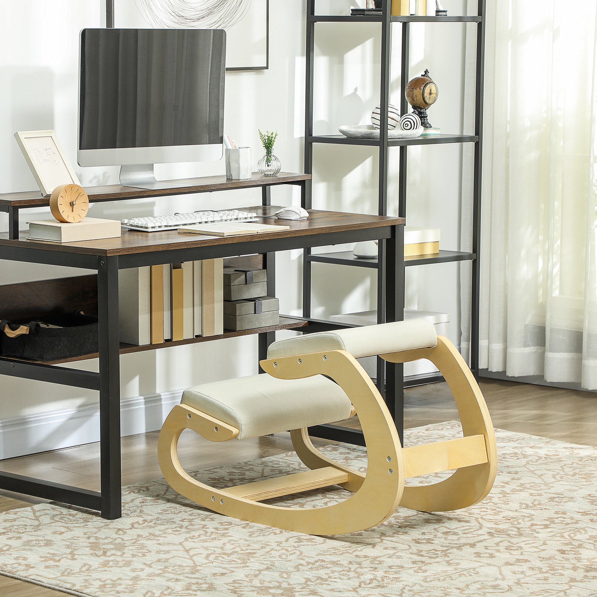 Uno sgabello ergonomico in legno davanti a una scrivania con monitor, libri e scaffale sullo sfondo.