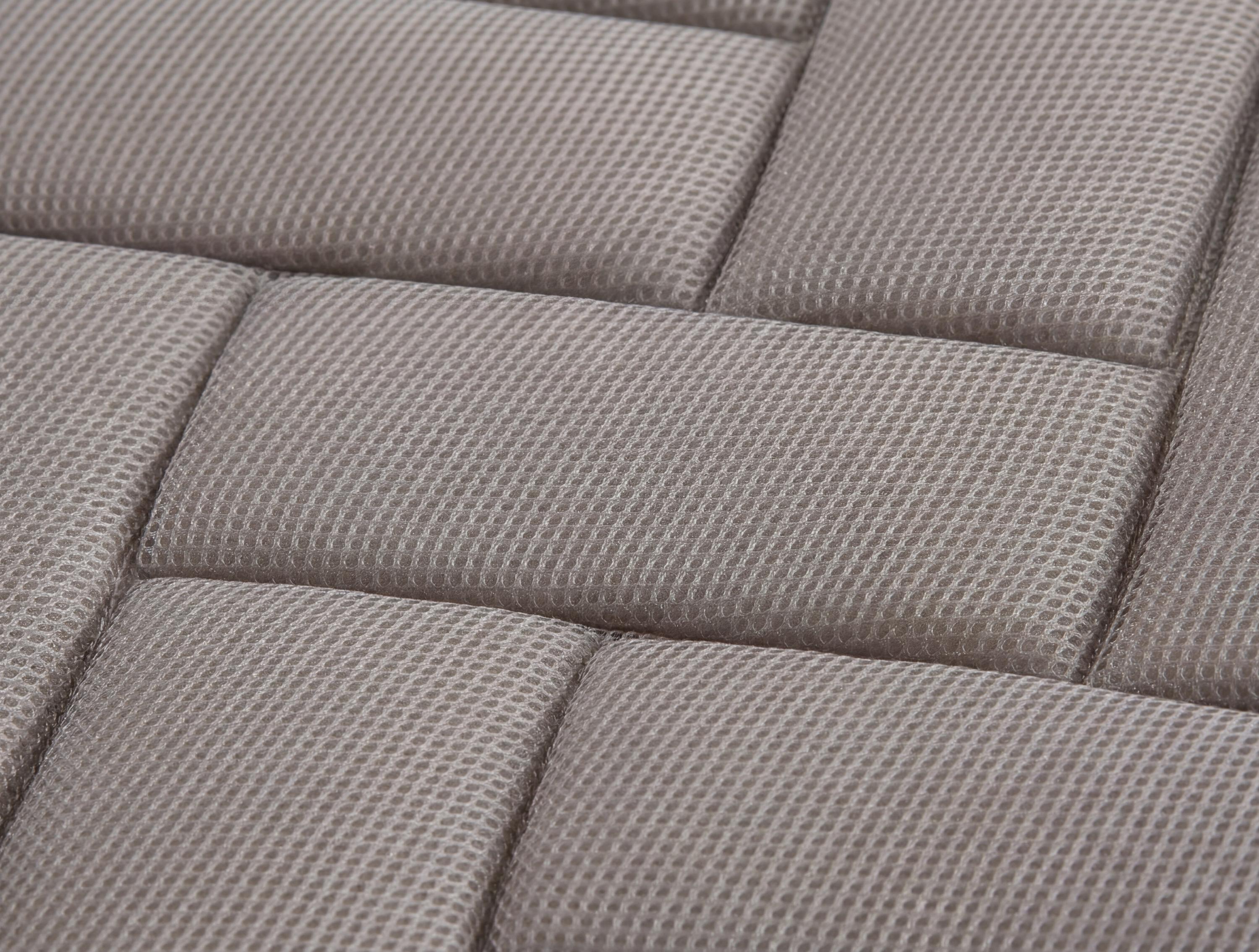 Primer plano de una superficie tapizada gris con un patrón texturizado en forma de malla en paneles rectangulares.