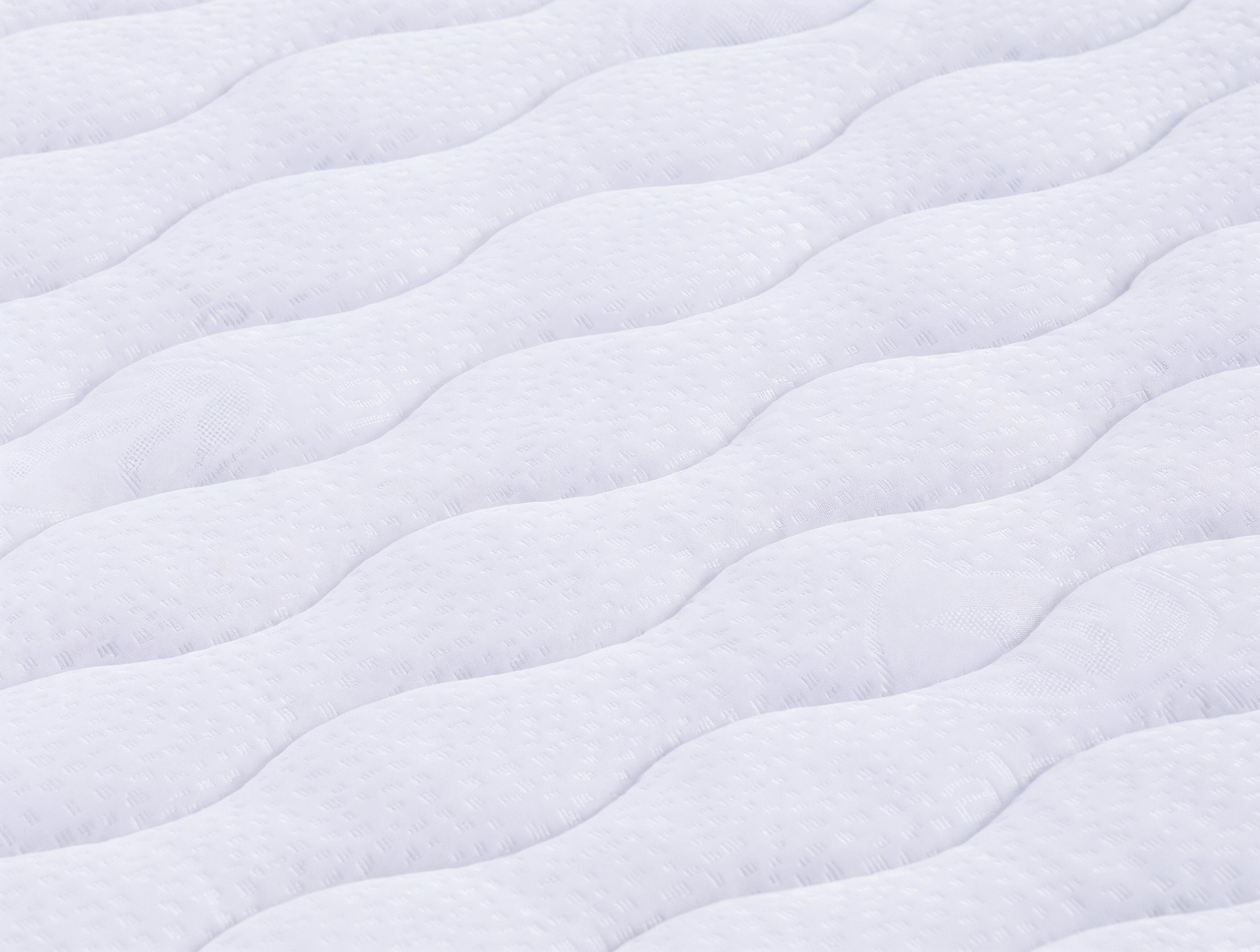 Primer plano de un colchón blanco con un patrón acolchado.