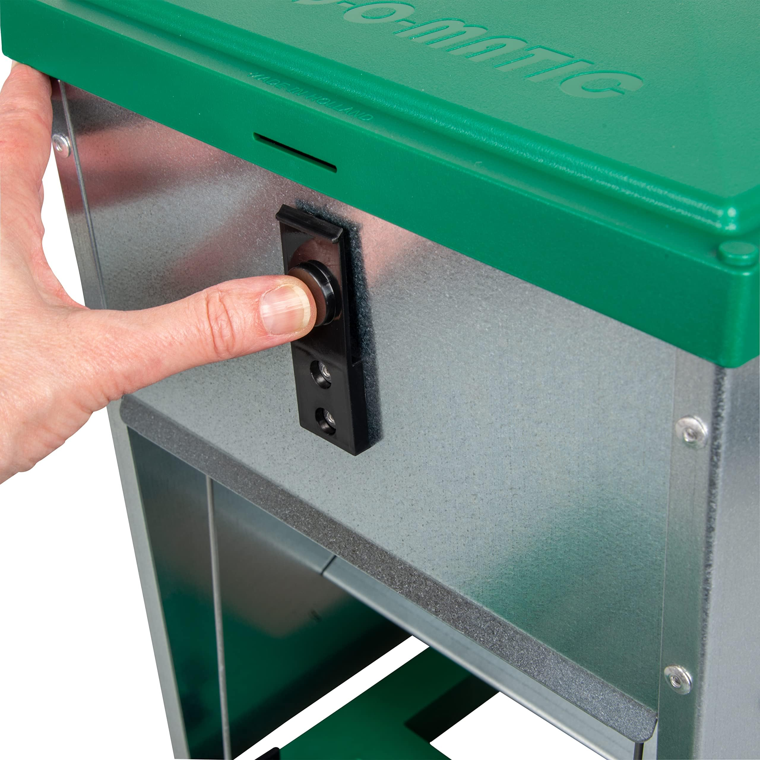 Una mano preme un pulsante nero su un corpo di erogatore metallico e verde.