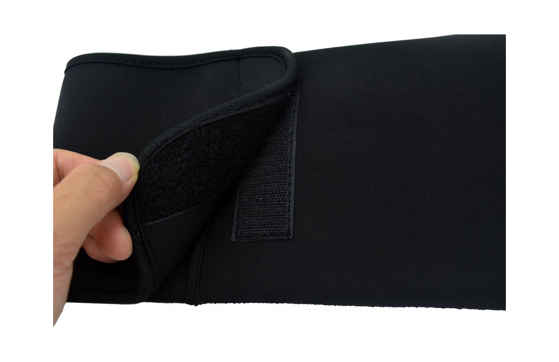 Eine Hand öffnet den Klettverschluss eines schwarzen Neopren-Sportgürtels vor weißem Hintergrund.