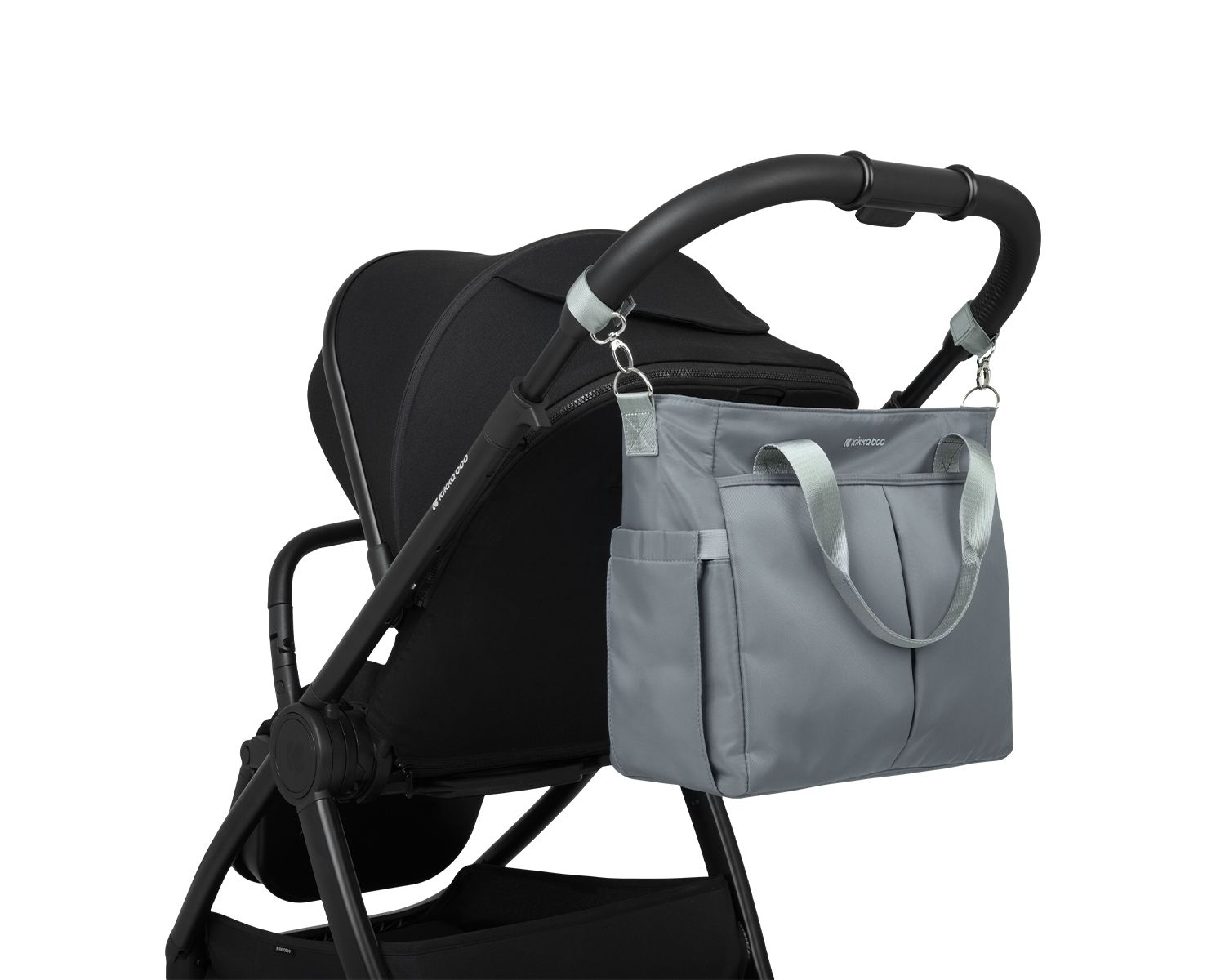 Eine graue Wickeltasche hängt am Schieber eines schwarzen Kinderwagens vor weißem Hintergrund.