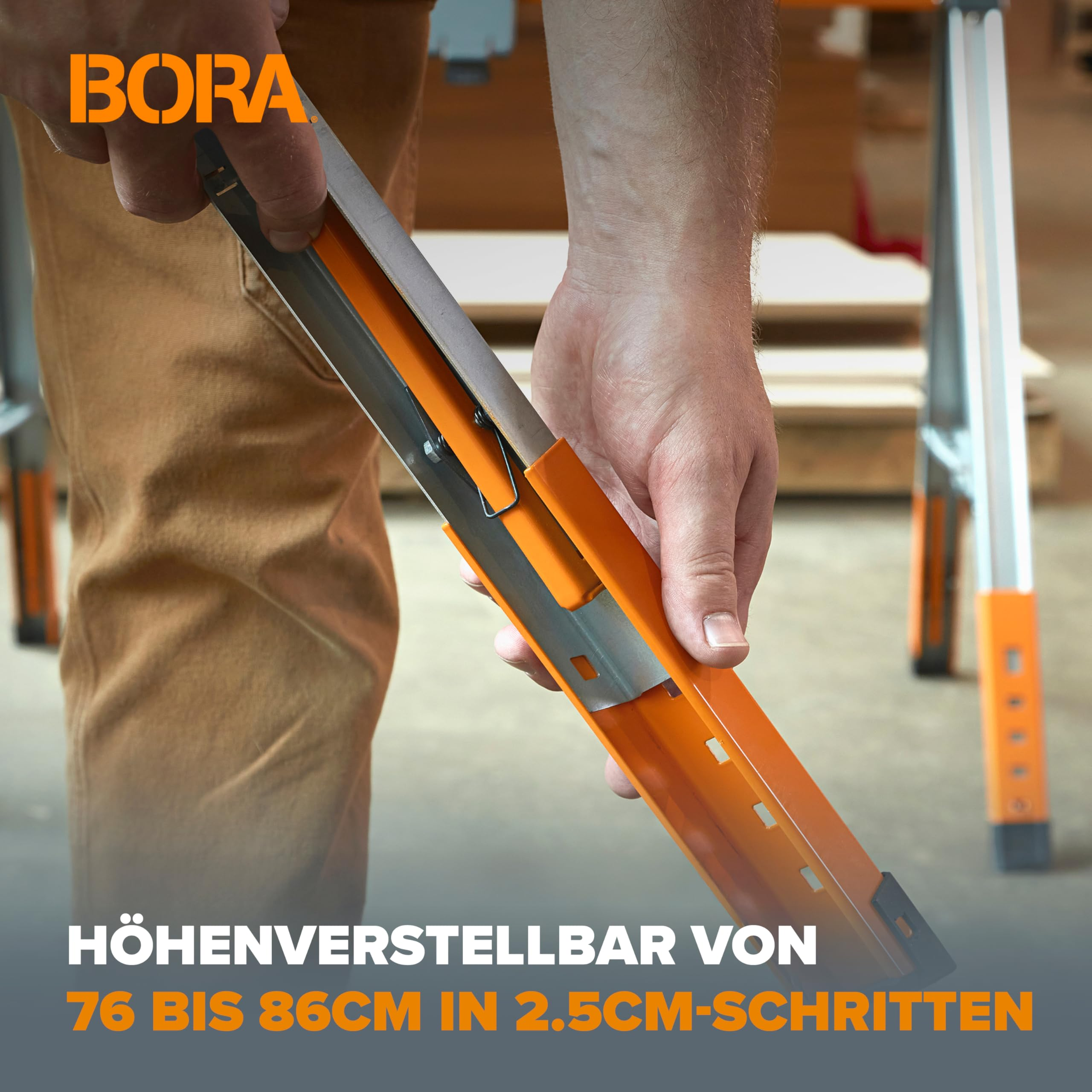 Eine Hand verstellt die Höhe eines orange-silbernen Bora-Sägebocks in einer Werkstatt.