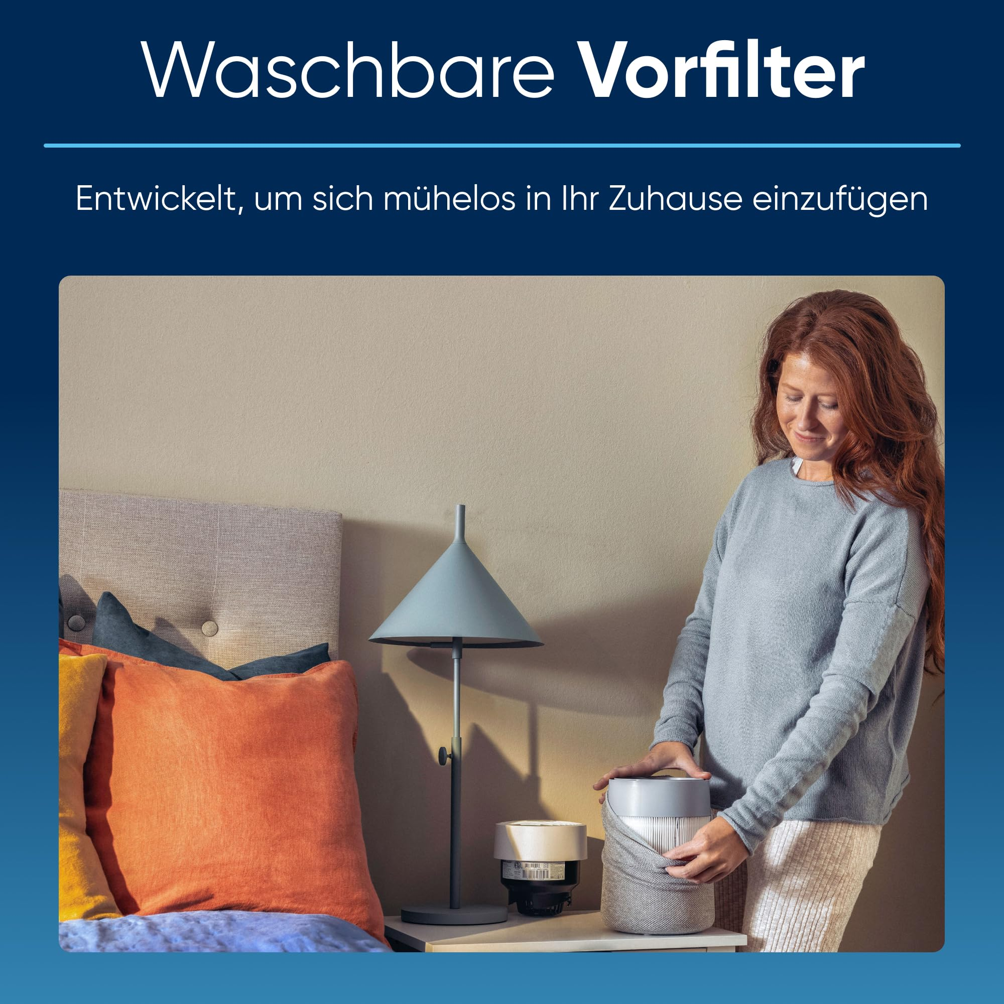 Eine Frau in einem Schlafzimmer setzt einen grauen Vorfilter auf ein Luftreinigungsgerät.
