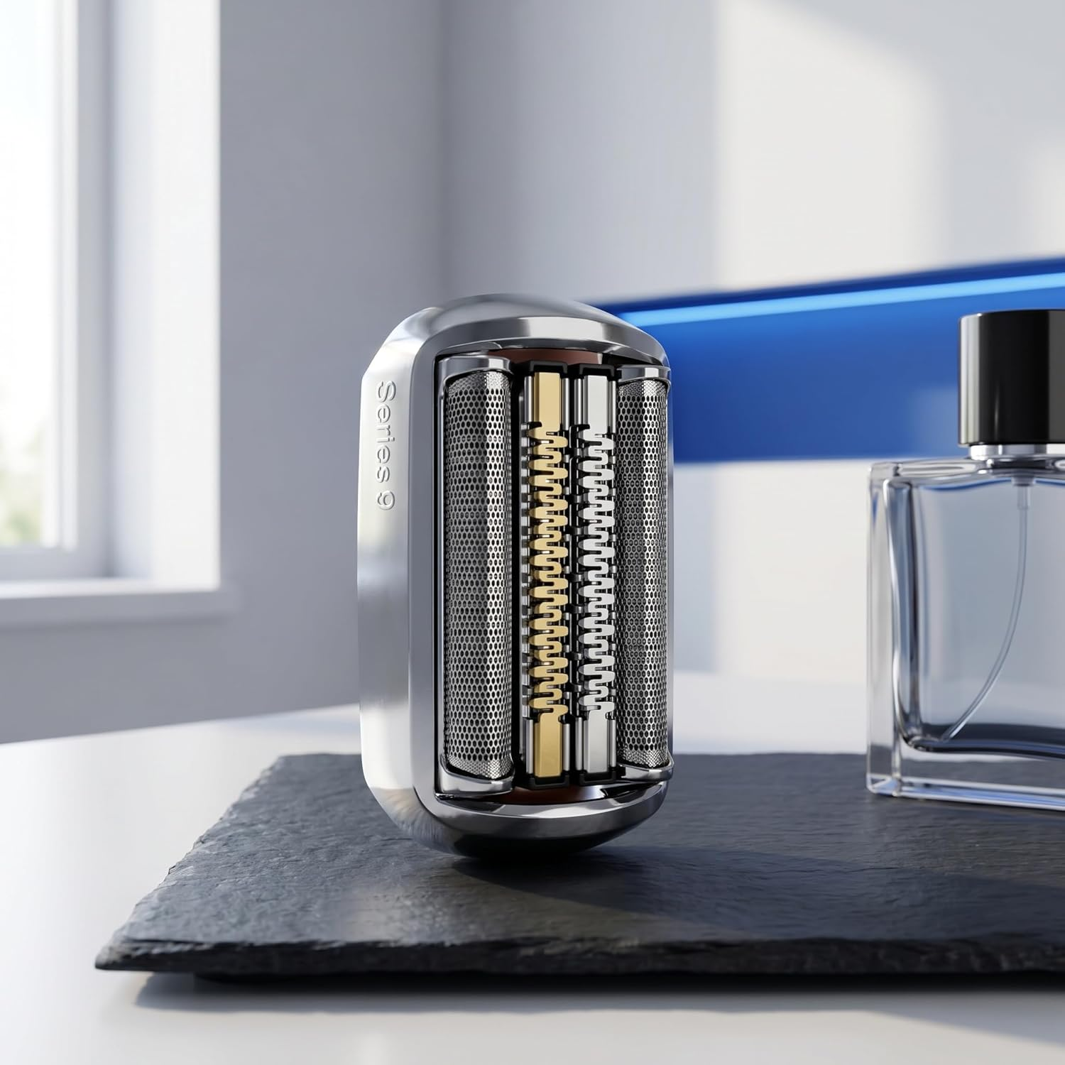 Ein Rasierkopf einer Series 9 Rasierers auf einer dunklen Platte neben einem Parfumflakon in einem hellen Raum.