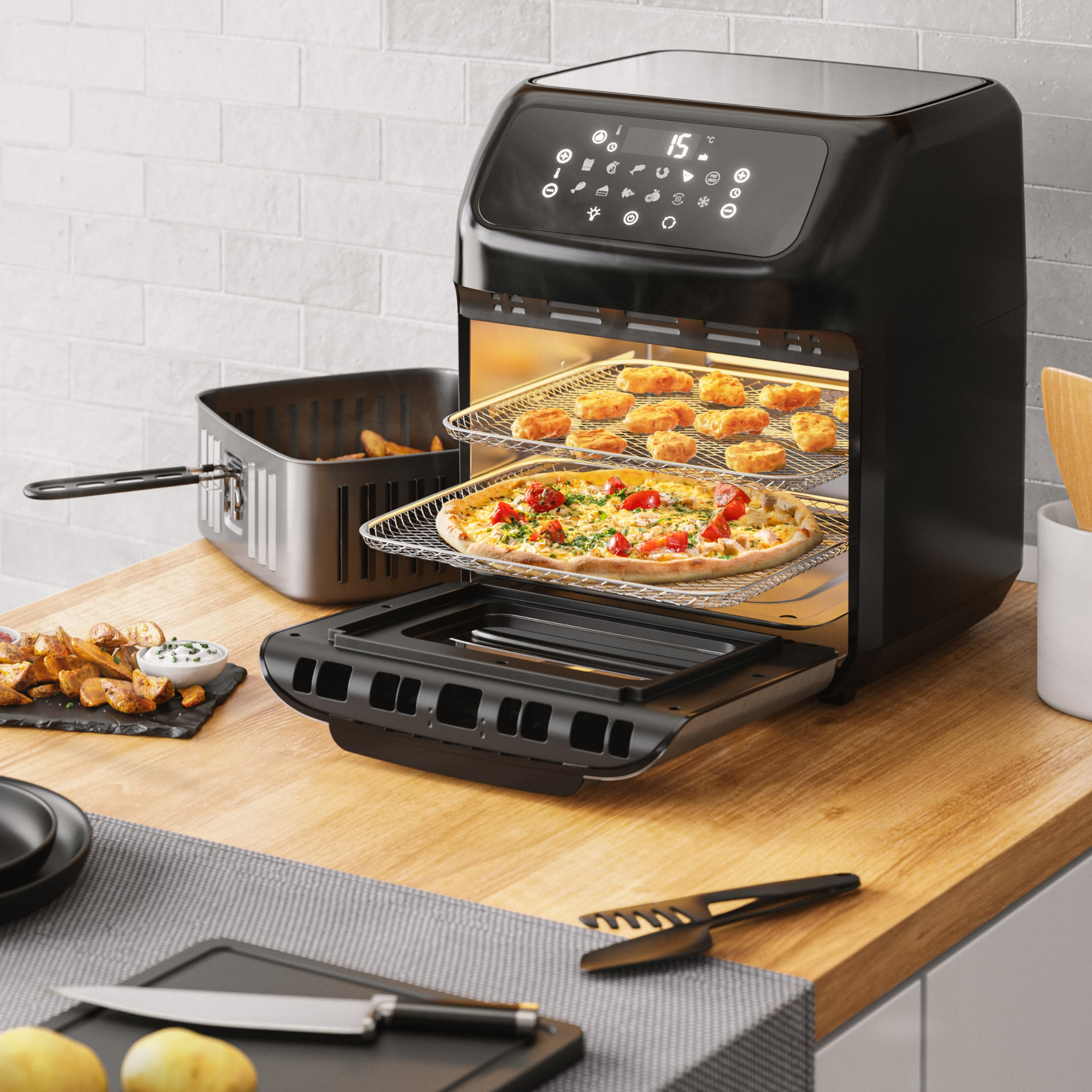 Une friteuse à air noire sur un comptoir en bois avec pizza et nuggets sur des grilles.