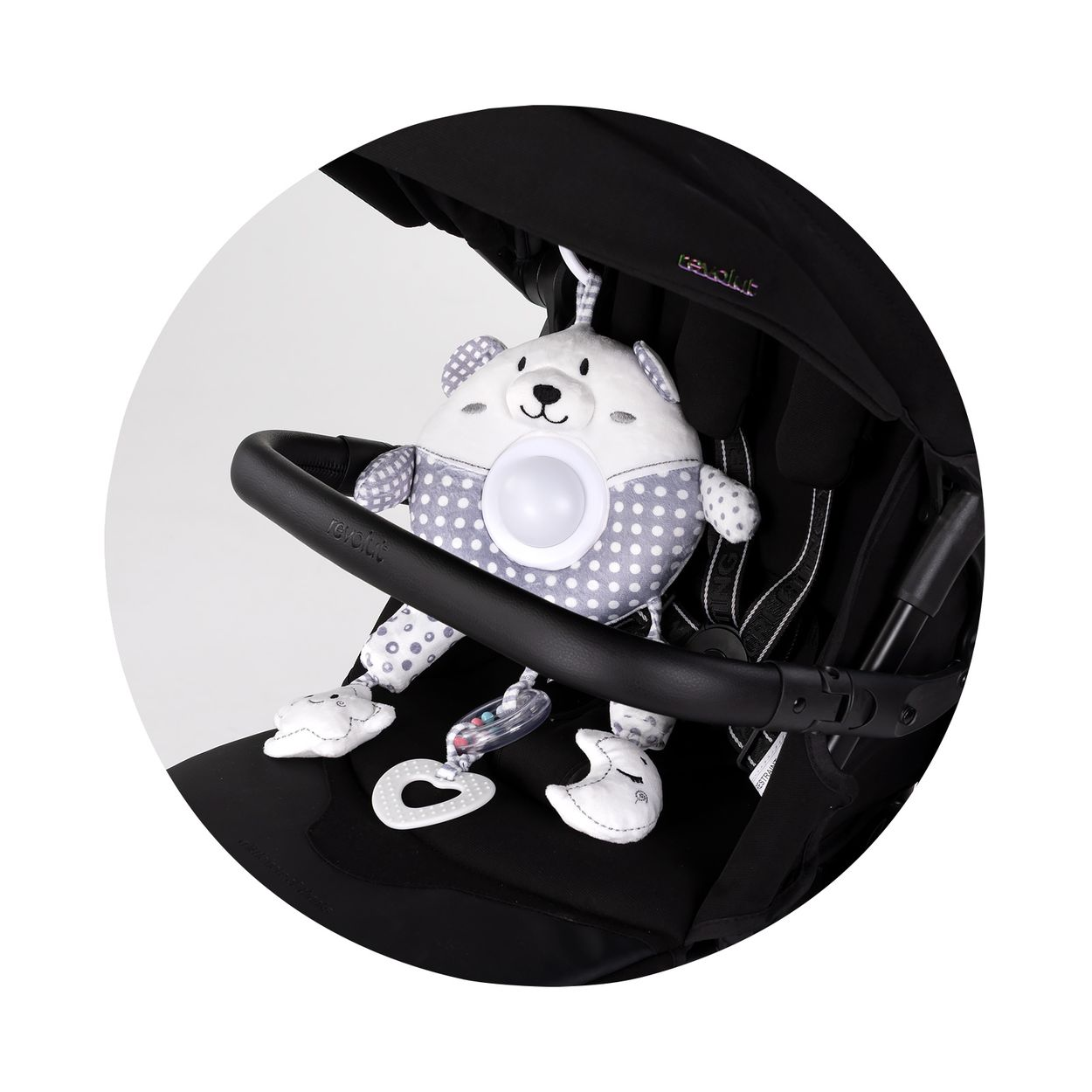 Ein weiß-grau gepunkteter Plüschbär hängt am Kinderwagendach, mit integriertem Spiegel und Spielzeug.