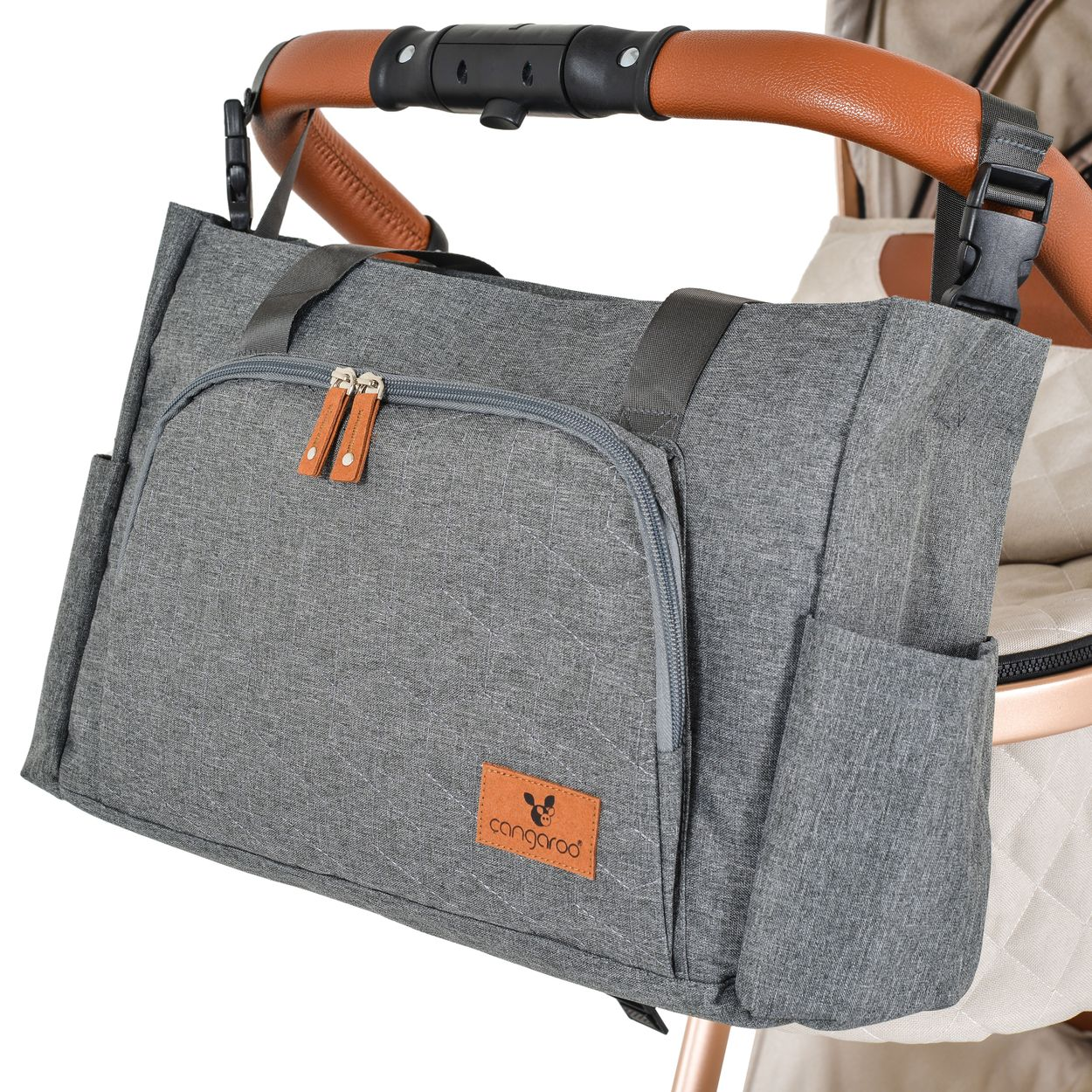 Eine graue Wickeltasche mit braunen Lederakzenten hängt am braunen Griff eines Kinderwagens.