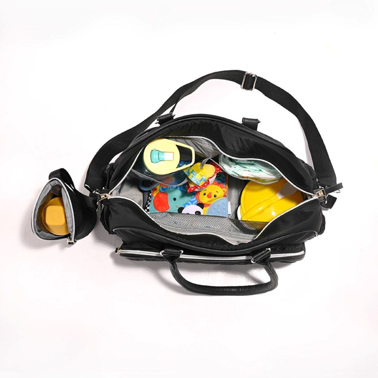 Eine offene schwarze Wickeltasche mit Babysachen, Spielzeug und Flaschen vor weißem Hintergrund.