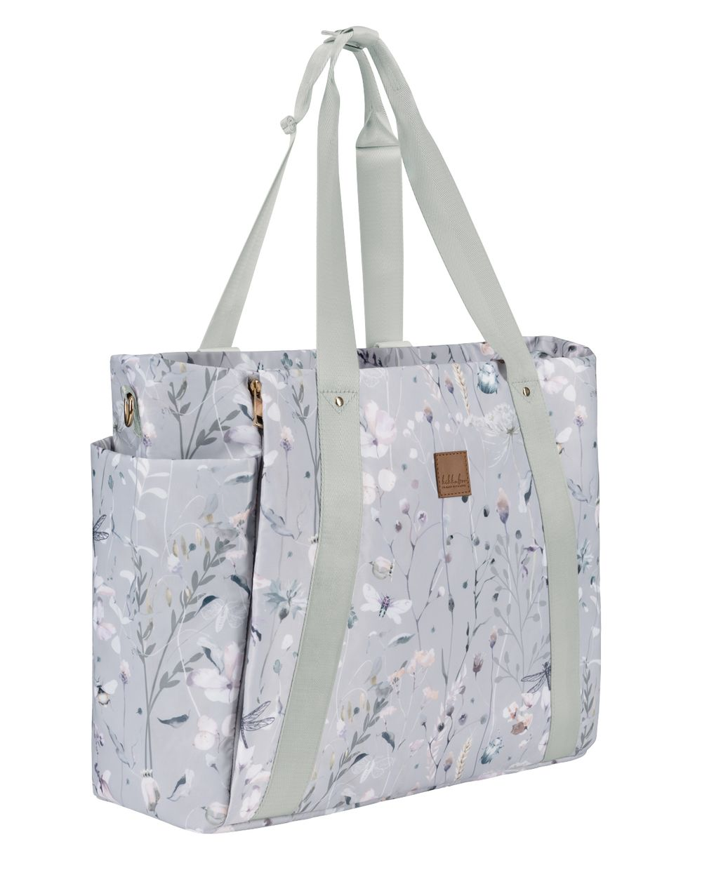 Eine graue Wickeltasche mit zarten Blumen und hellgrünen Trägern vor weißem Hintergrund.