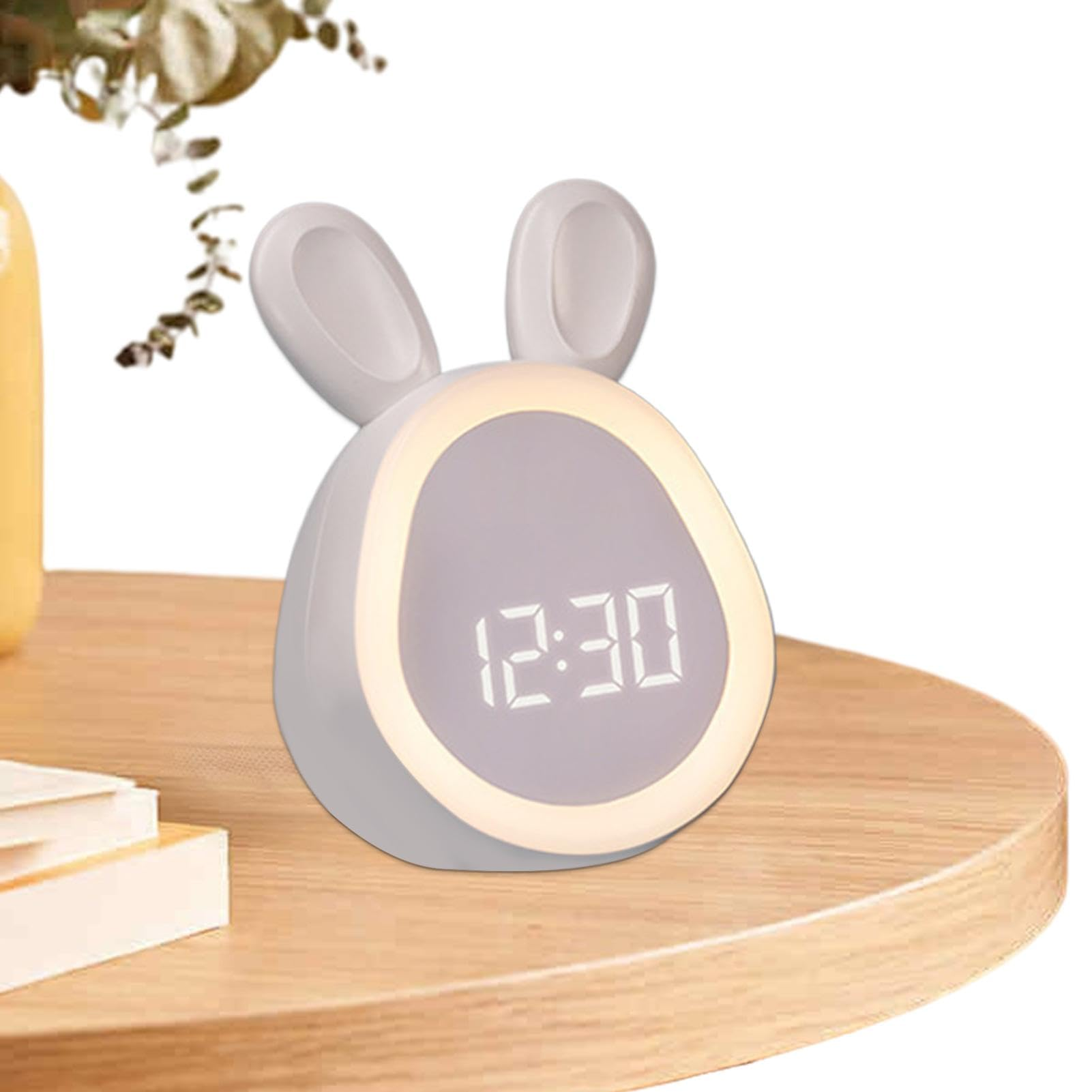 Ein süßer hasenförmiger Digitalwecker mit Leuchtring und großen Ziffern steht auf einem Holztisch.