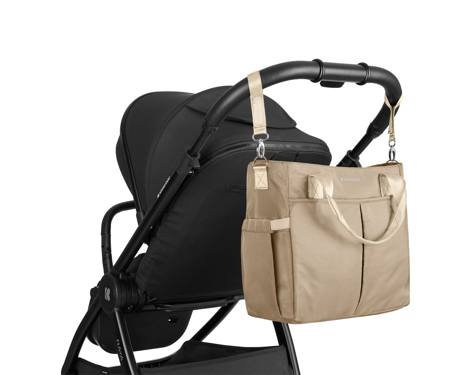 Eine beige Wickeltasche mit goldenen Riemen hängt am Lenker eines schwarzen Kinderwagens vor weißem Hintergrund.