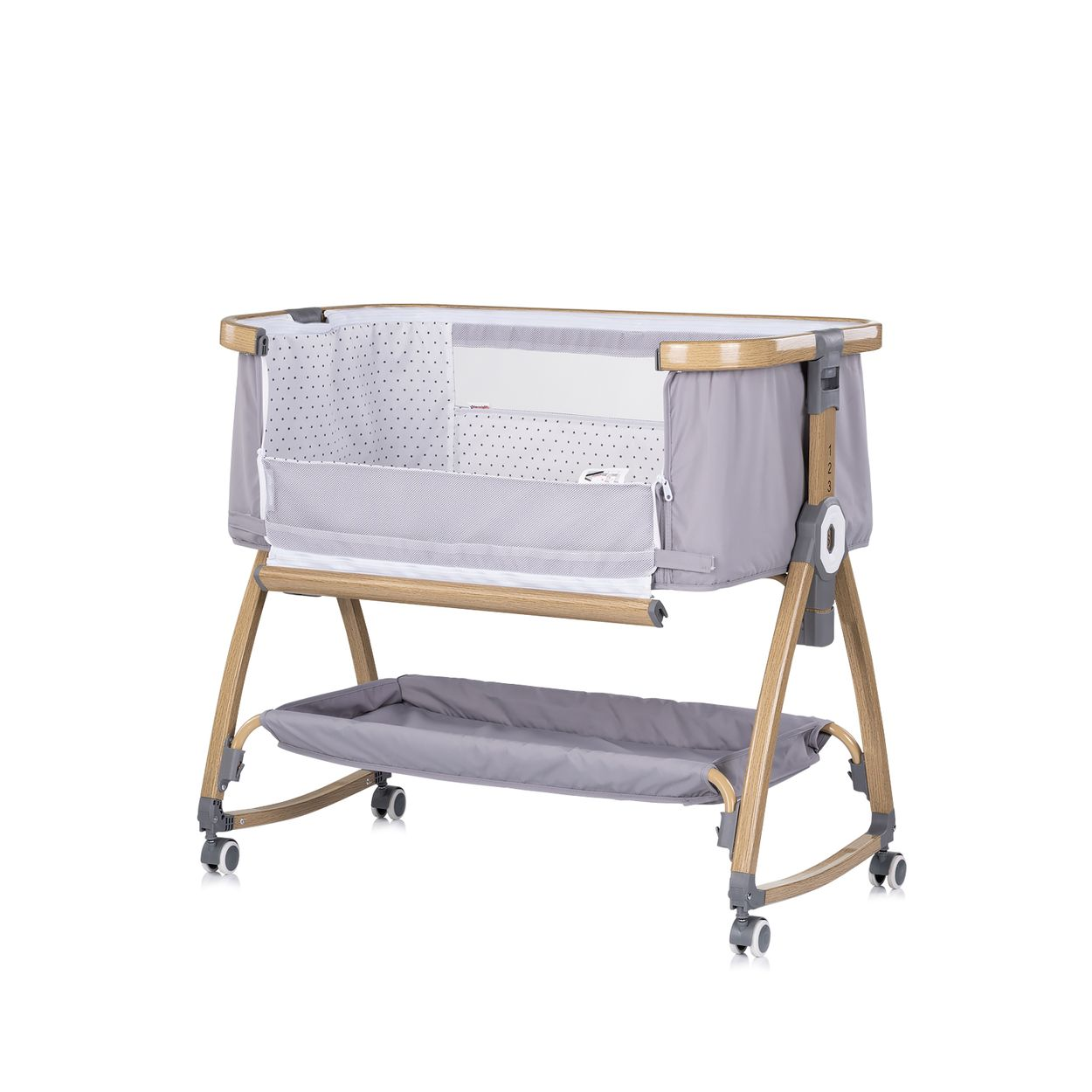 Ein graues Babybett mit Pünktchenmuster, Holzgestell, Rollen und Ablagefach.