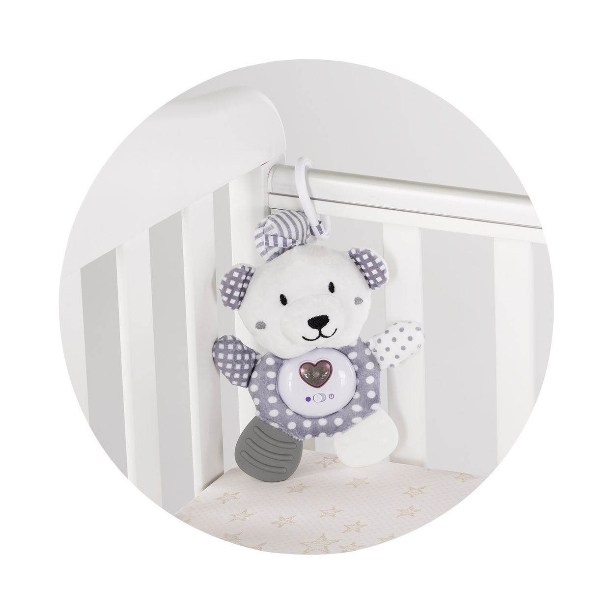 Ein weiß-grauer Plüsch-Teddybär hängt an einem weißen Gitterbett mit Sternenmuster.