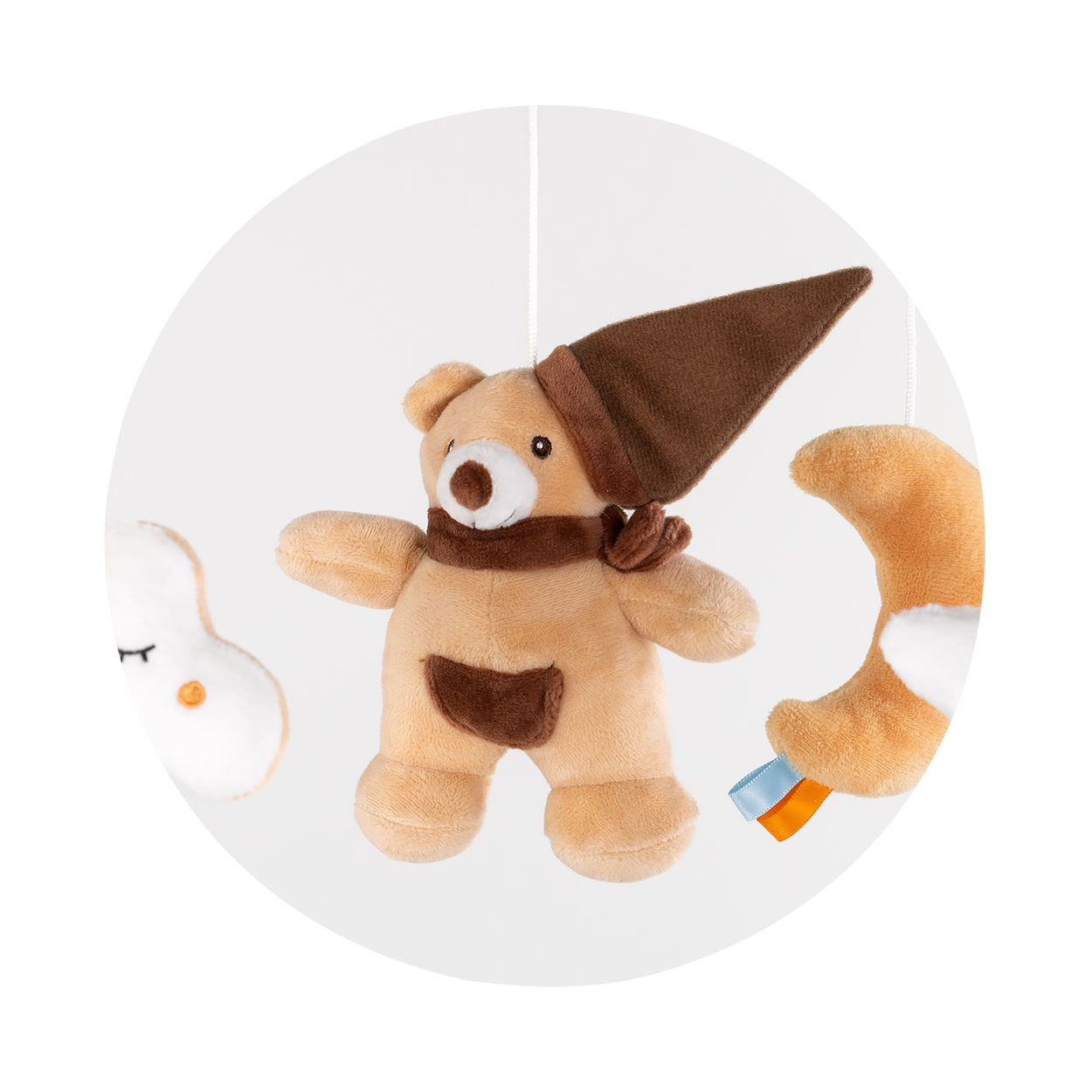 Ein Plüschbär mit brauner Mütze und Schal hängt zusammen mit einer Wolke und einem Mond an einem Mobile.