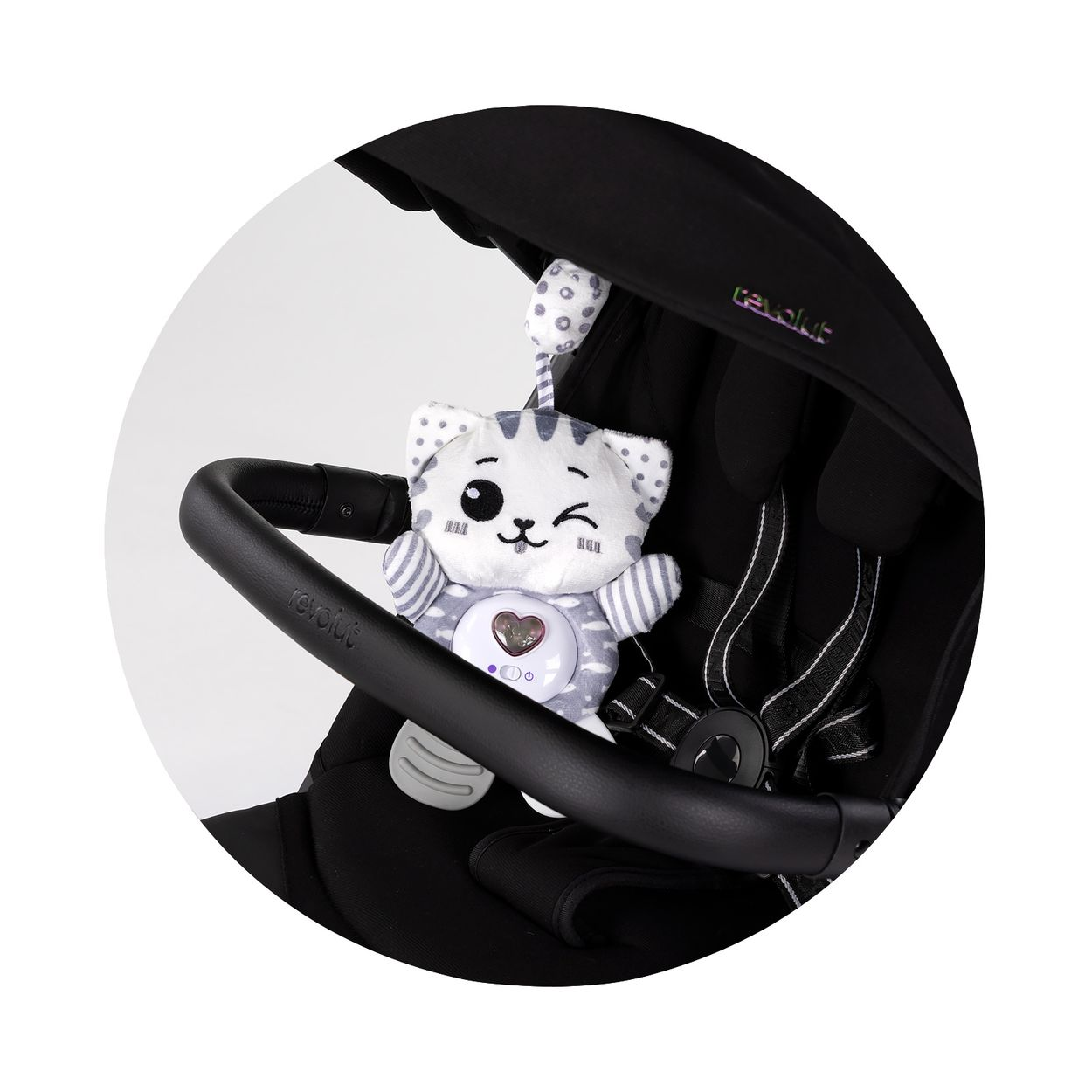 Ein süßes grau-weißes Kuschelkatzenspielzeug hängt am Lenker eines schwarzen Kinderwagens.
