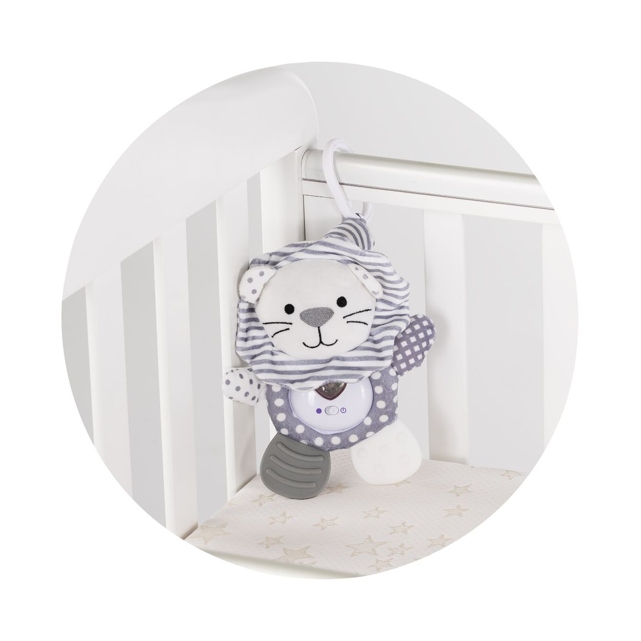 Ein grauschwarzes Kuscheltier mit Streifenmuster und Rassel hängt am weißen Babybett.