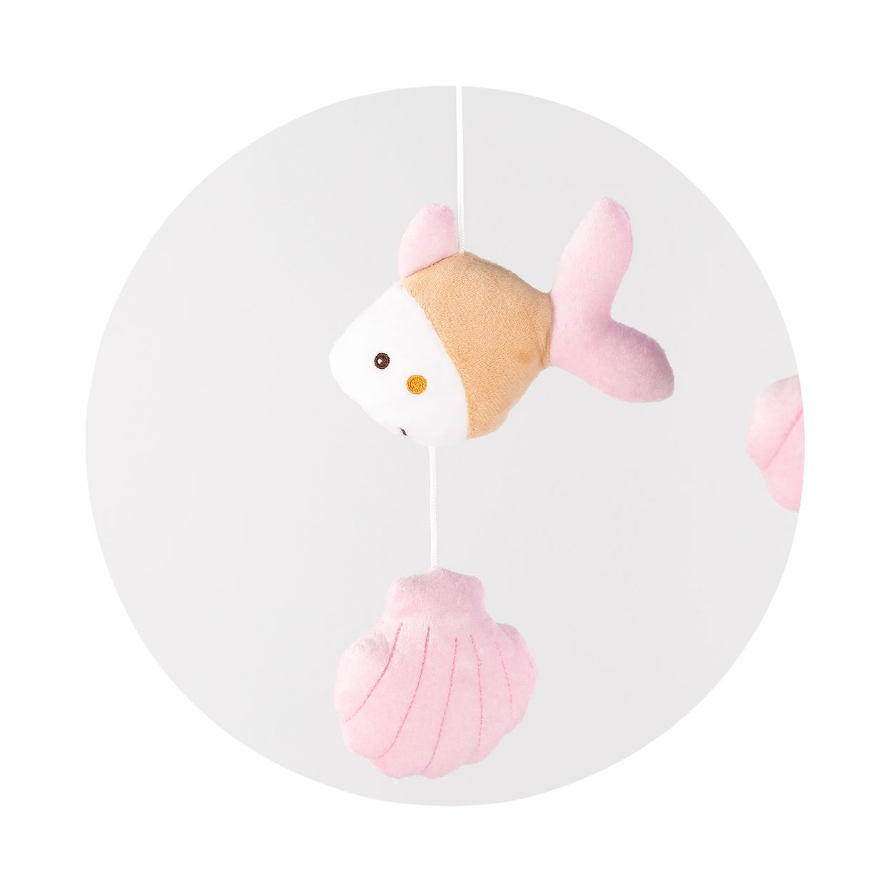 Ein Plüschtier mit einem rosa Fisch und einer Muschel an Schnüren.