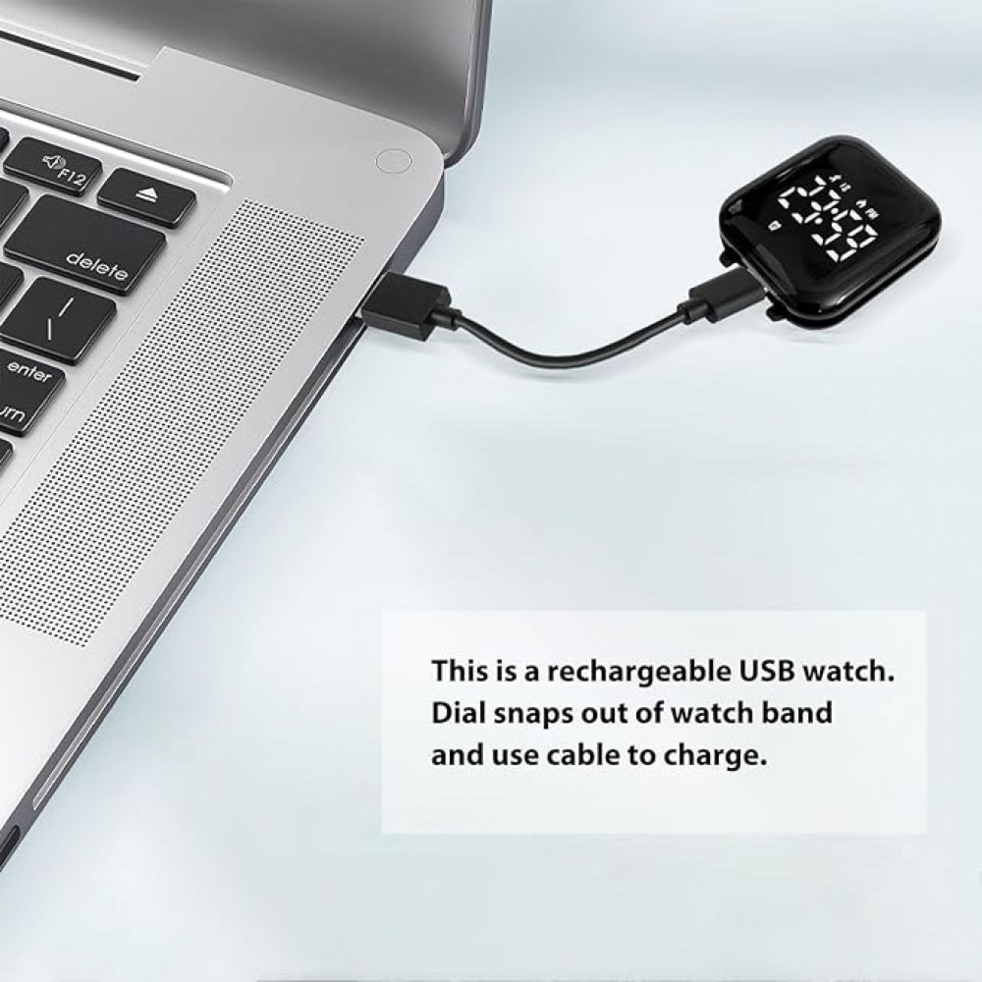 Eine schwarze digitale Uhr lädt über USB-Kabel an einem Laptop auf einer weißen Oberfläche.