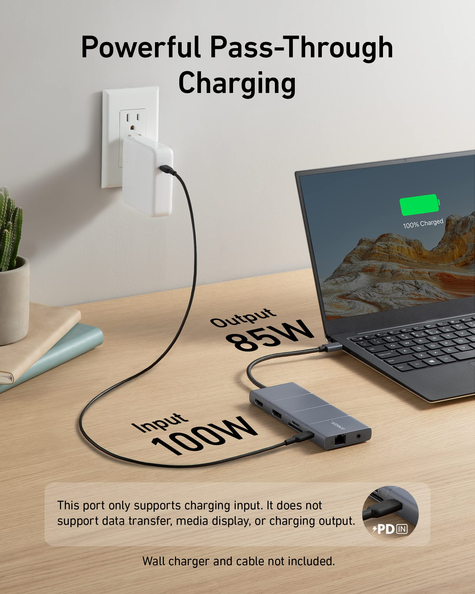 Un hub USB-C grigio su una scrivania in legno carica un computer portatile a 85W, collegato a un caricatore a muro.