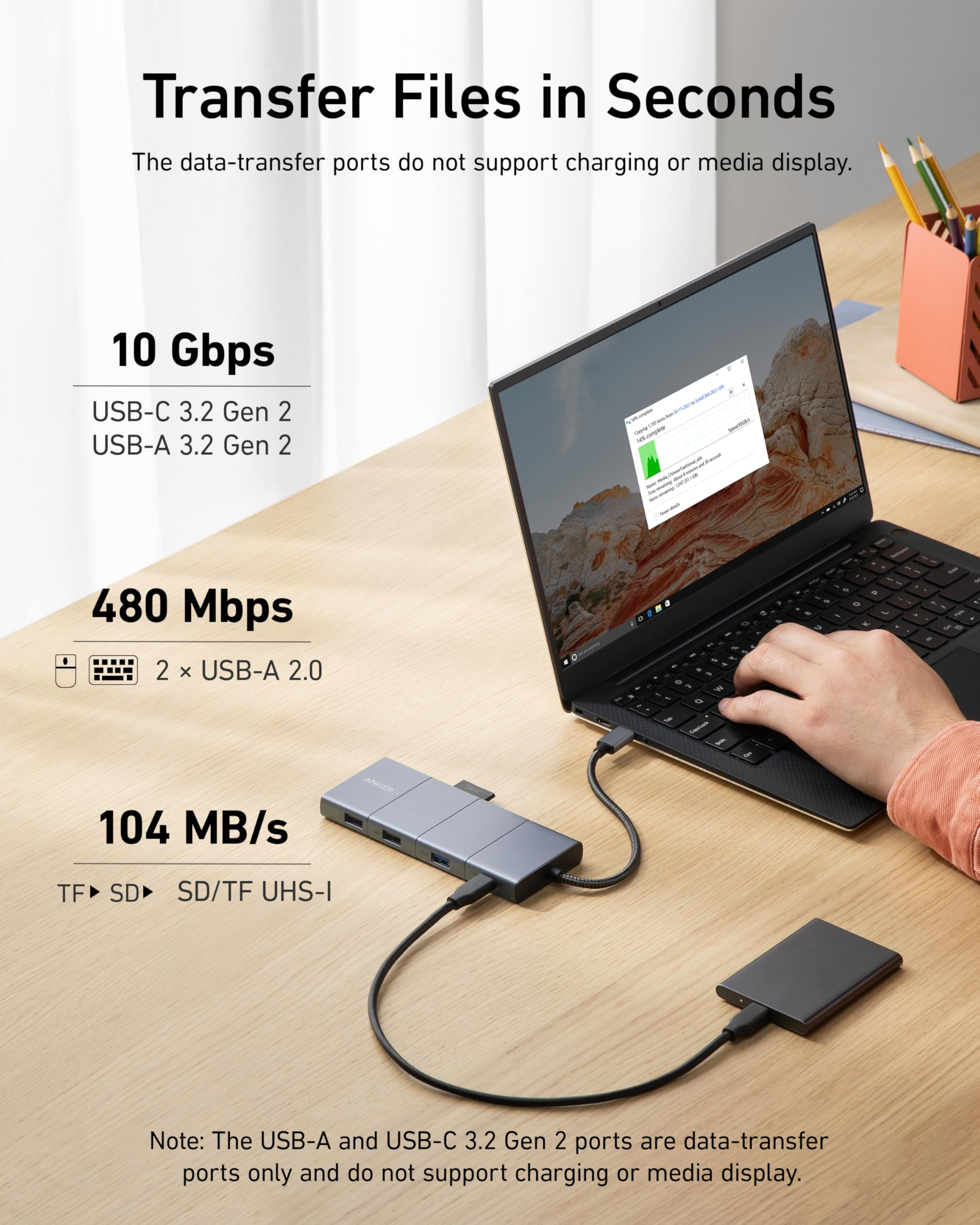 Un hub USB-C grigio su una scrivania in legno è collegato a un laptop e a un disco rigido esterno.