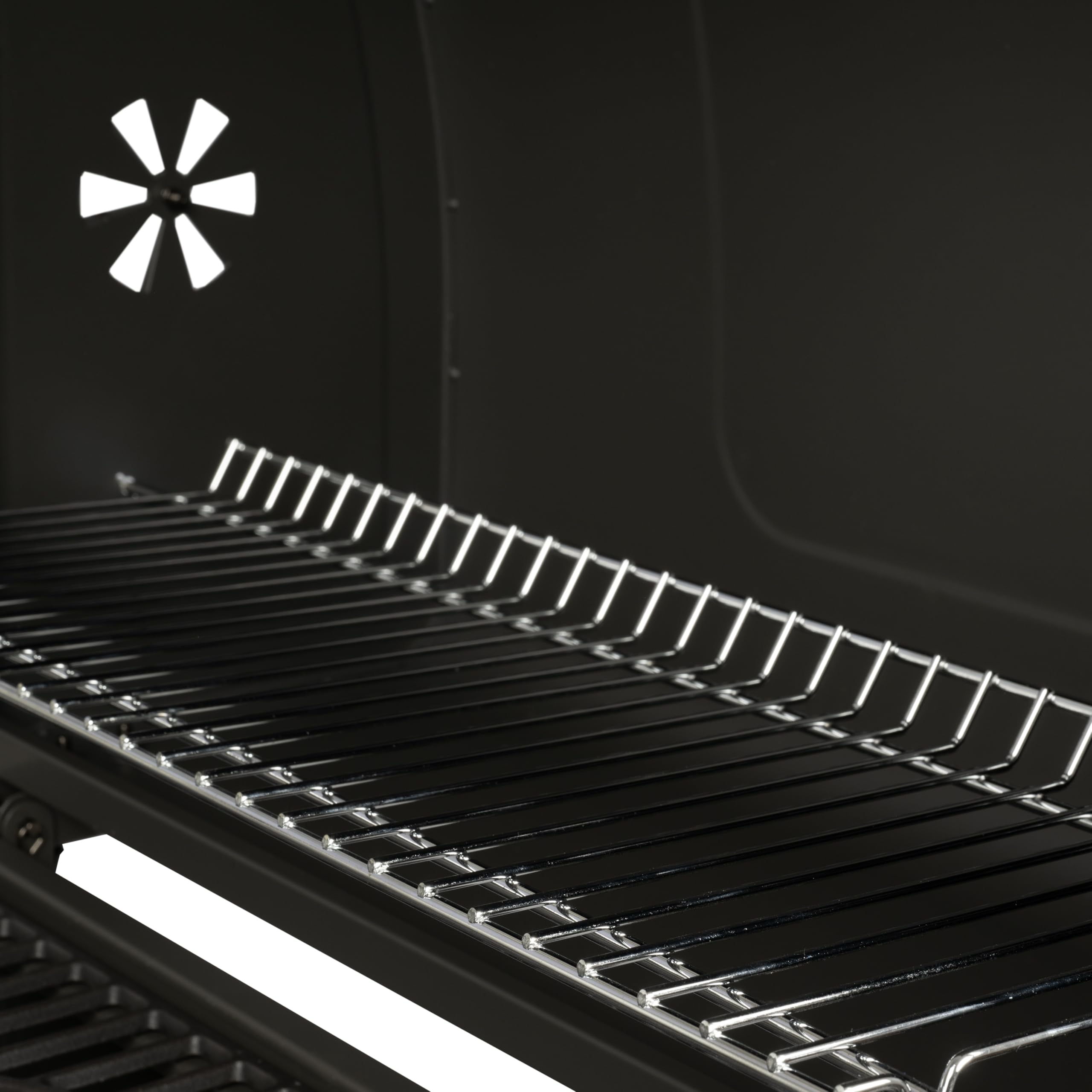 Vue intérieure d'un fumoir noir avec grilles métalliques brillantes et ventilation.