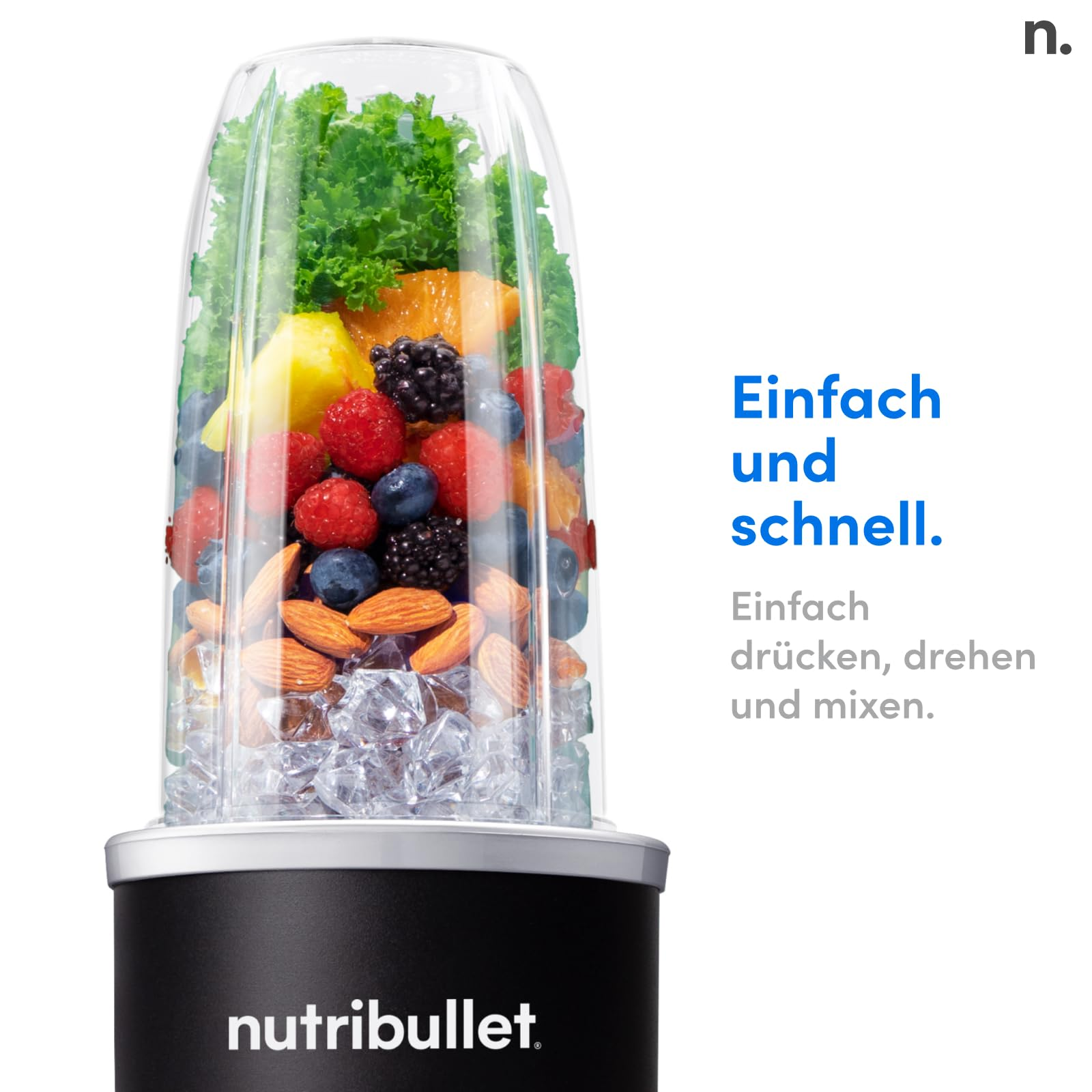 Un gobelet de blender Nutribullet rempli de glaçons, de noix, de baies et de verdure.