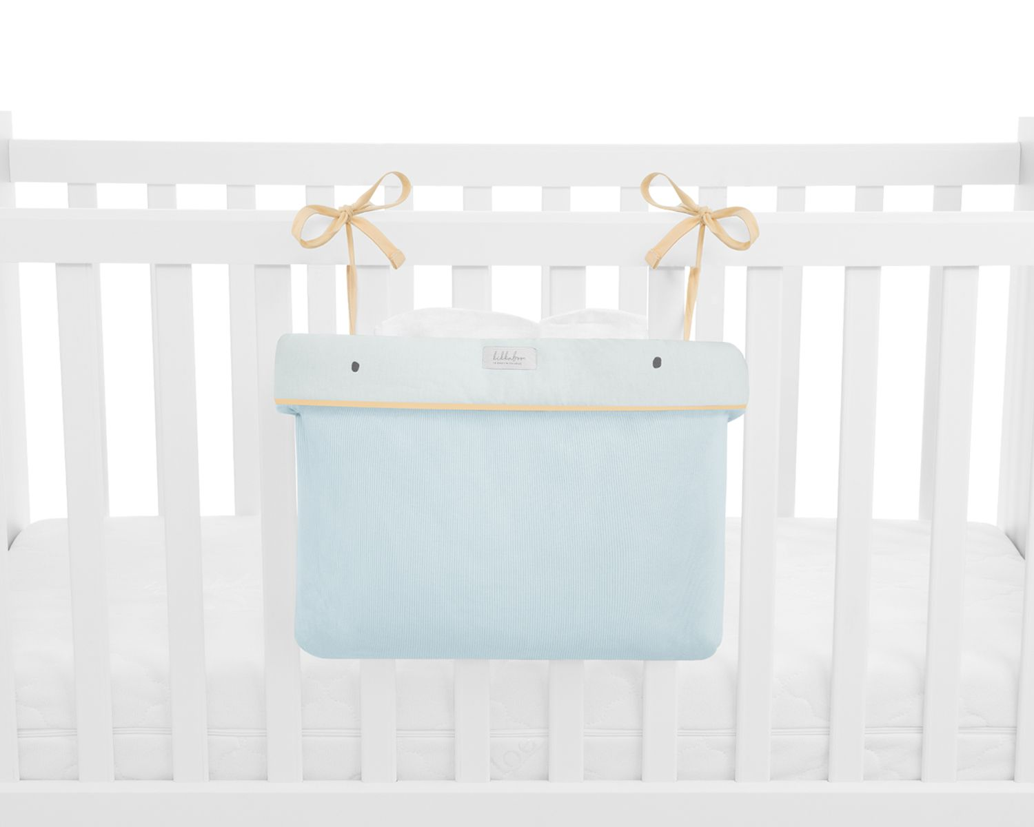 Hellblaue Organizer-Tasche mit gelben Schleifen, befestigt am weißen Gitterbett.