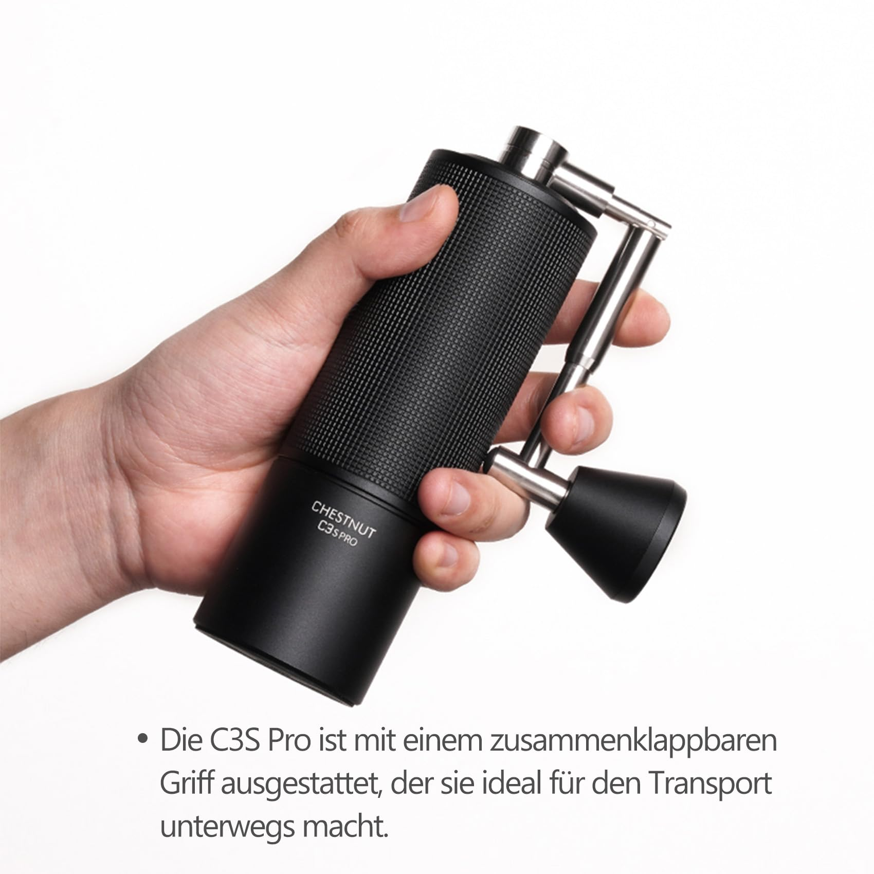 Eine Hand hält die schwarze Kaffeemühle Chestnut C3S Pro mit klappbarem Griff vor weißem Hintergrund.